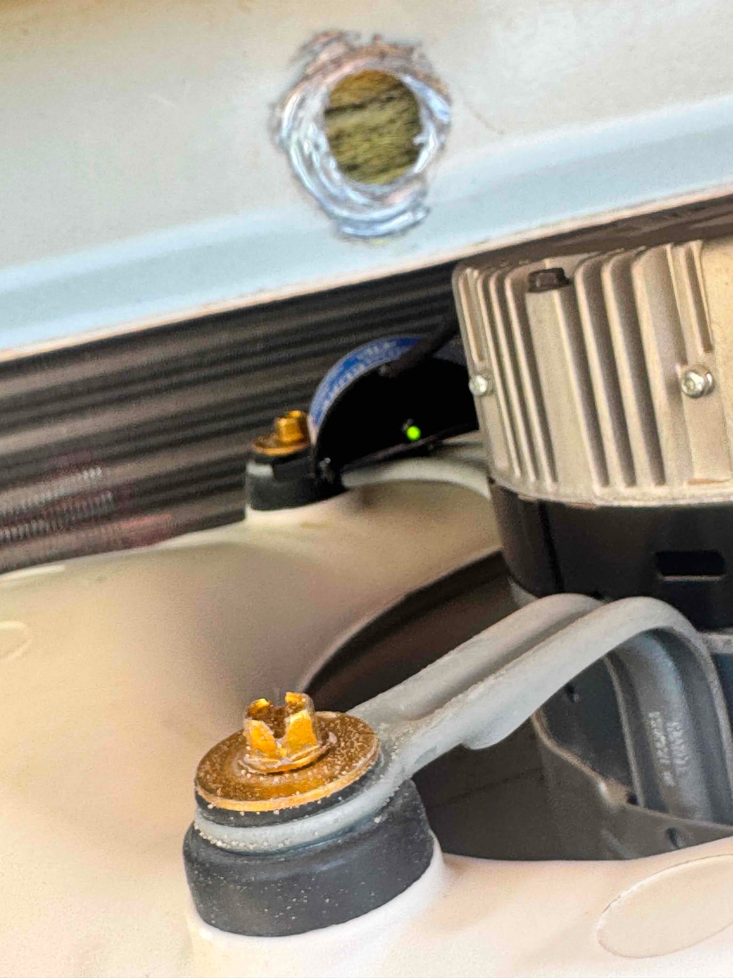 Close-up of condenser fan motor mount and rubber isolator with brass fasteners, showing coil fins and wiring inside the outdoor unit.