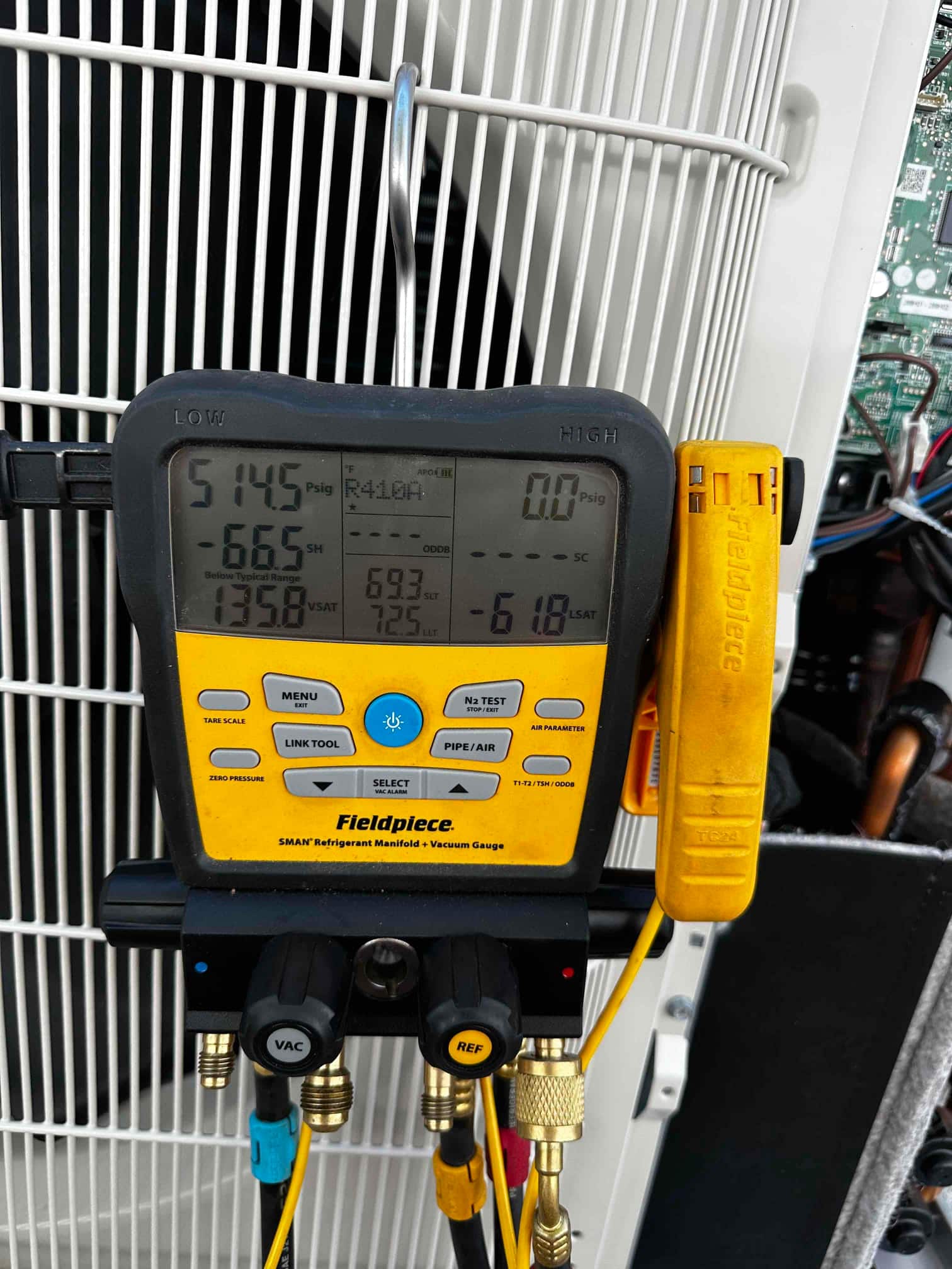 Digital manifold connected at the outdoor unit shows operating pressures with R-410A selected during system commissioning.