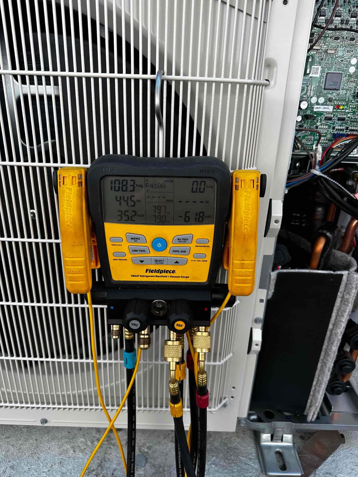 Digital manifold connected to the outdoor unit shows operating pressures with R-410A selected during system commissioning.