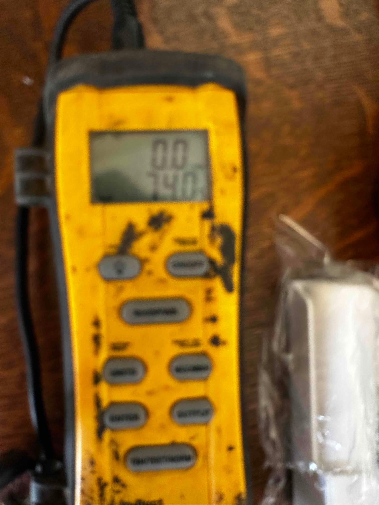 Digital thermometer with probe displays 74.0 degrees Fahrenheit, documenting return air temperature during commissioning.