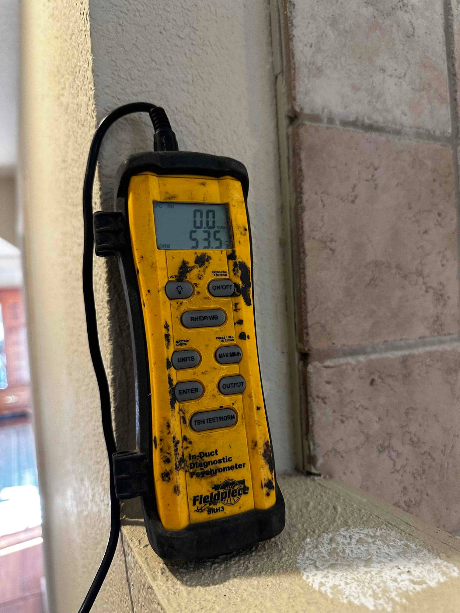 Digital thermometer shows 53.5 degrees, documenting cooled supply air temperature during system commissioning.