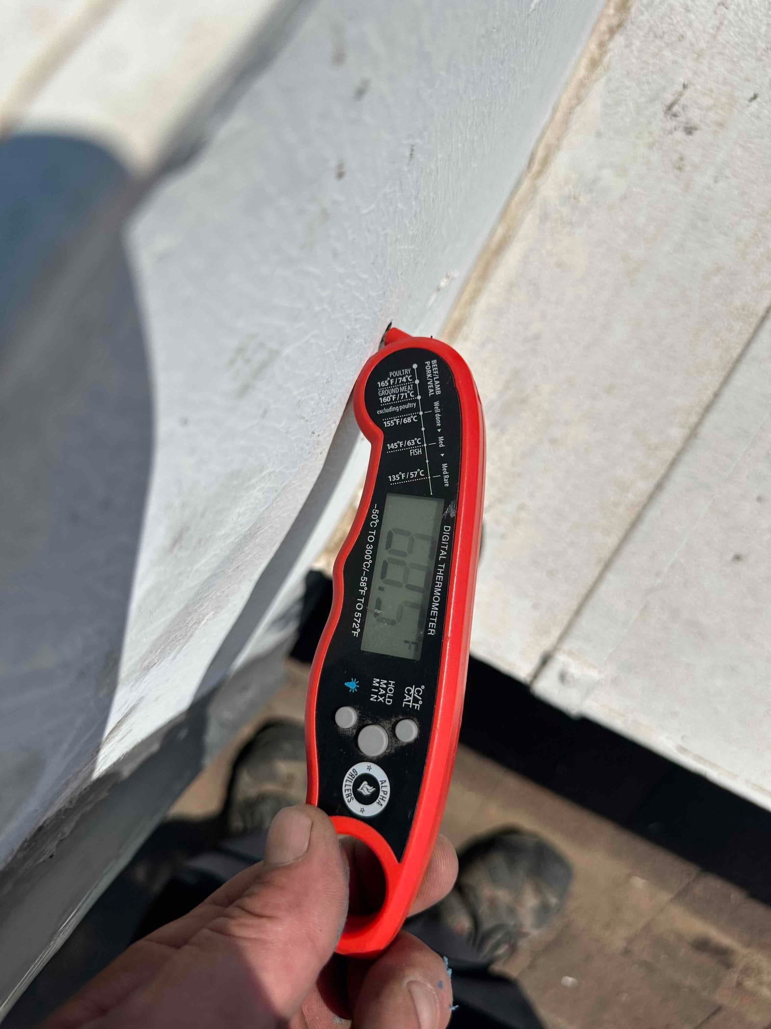 Digital thermometer shows 60.7°F while checking air temperature during commissioning of the newly installed system.