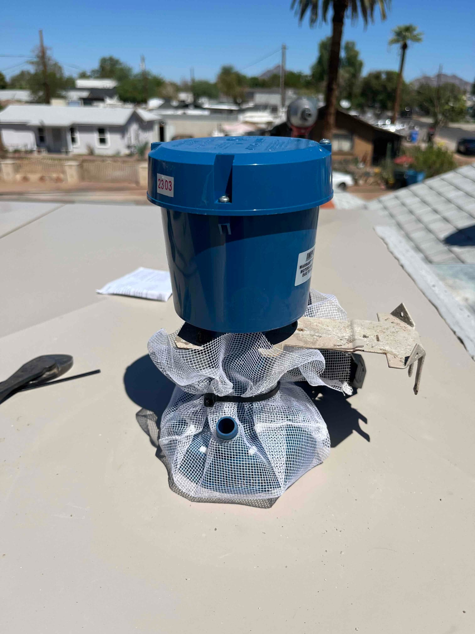 Evaporative cooler stand pipe assembly on rooftop, showing new blue top, mesh strainer, and mounting hardware.