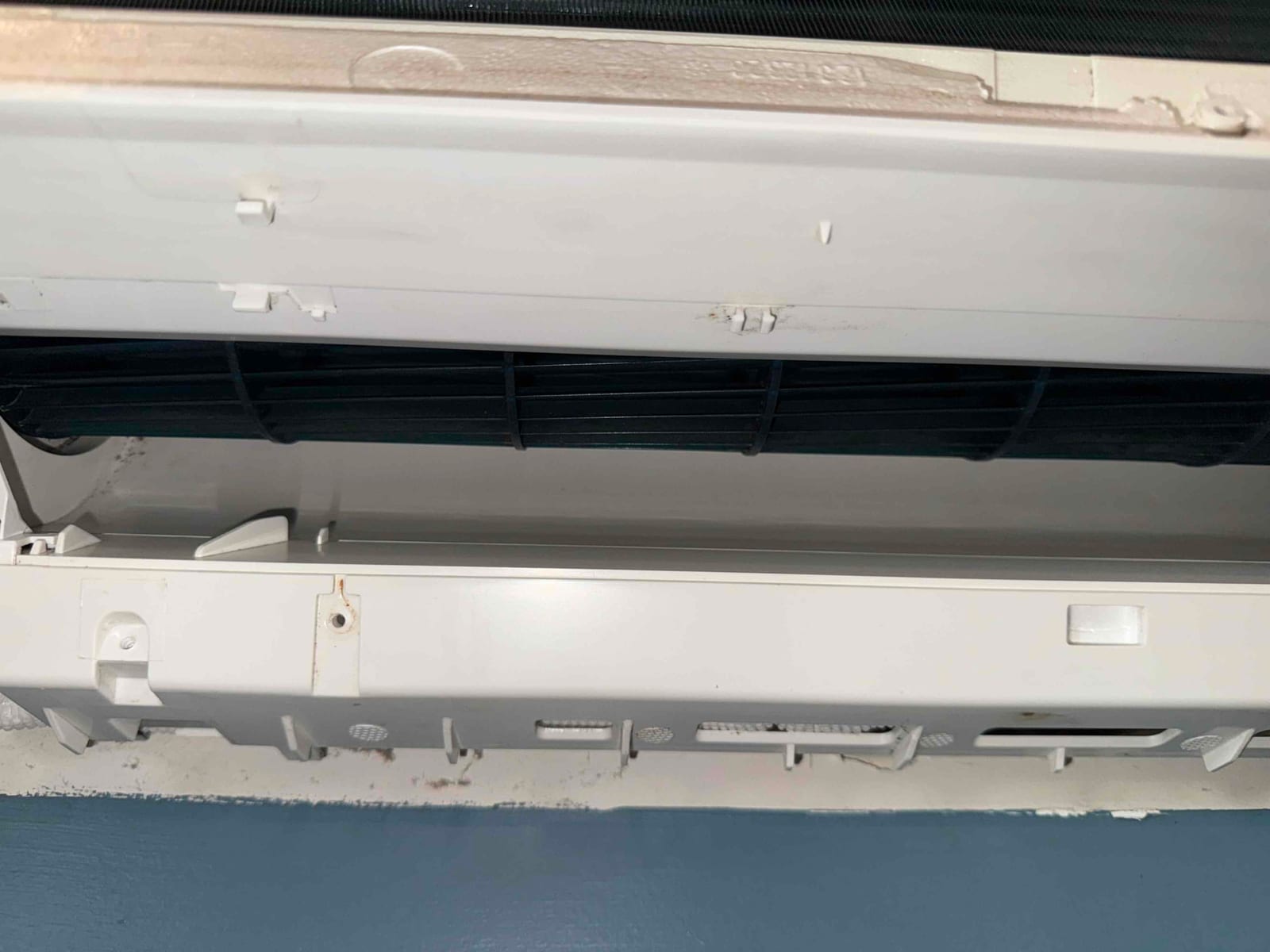 Mini-split indoor air handler with front cover open, showing evaporator coil and blower wheel for cleaning access.