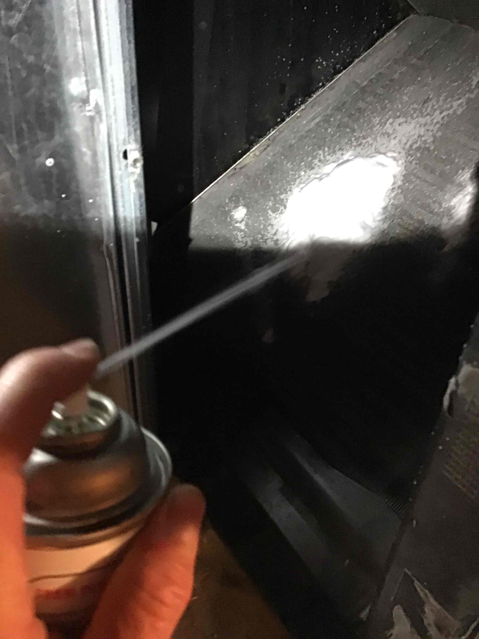 Aerosol spray is applied to the evaporator coil fins inside the air handler compartment.