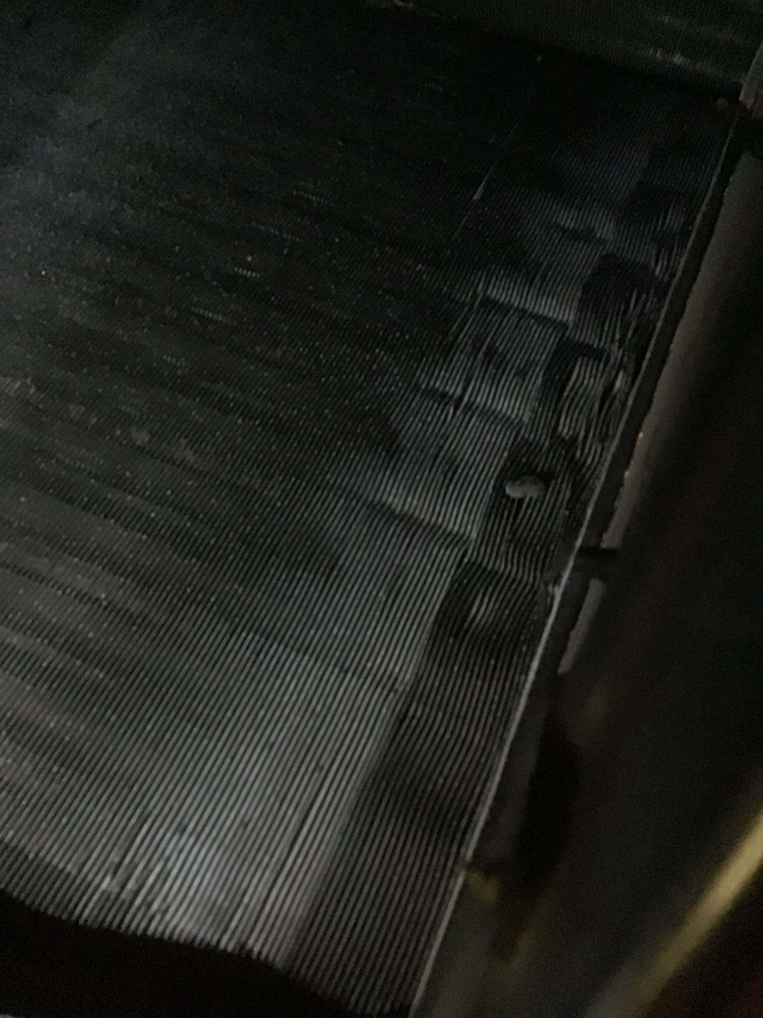 Close-up of HVAC coil fins with visible flattened sections and bent areas along the surface.