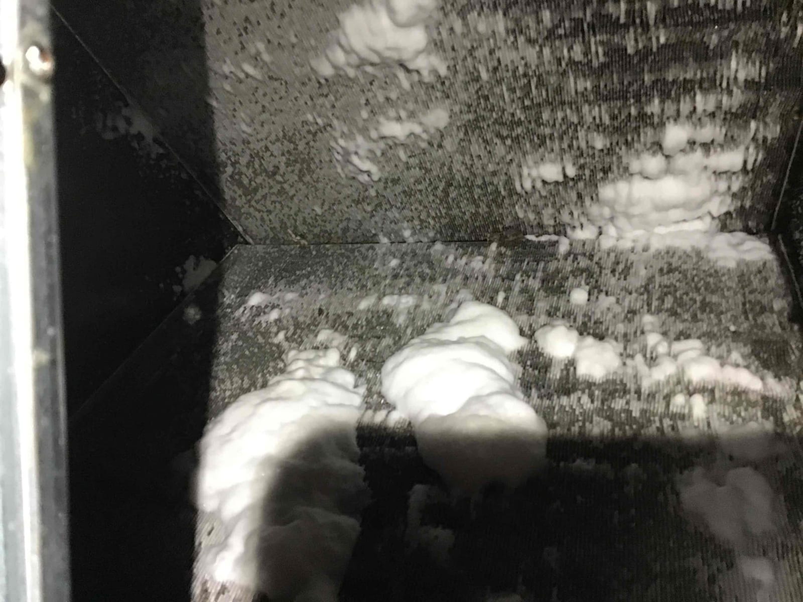 Coil fins inside the indoor HVAC cabinet show thick ice accumulation across multiple surfaces and corners.