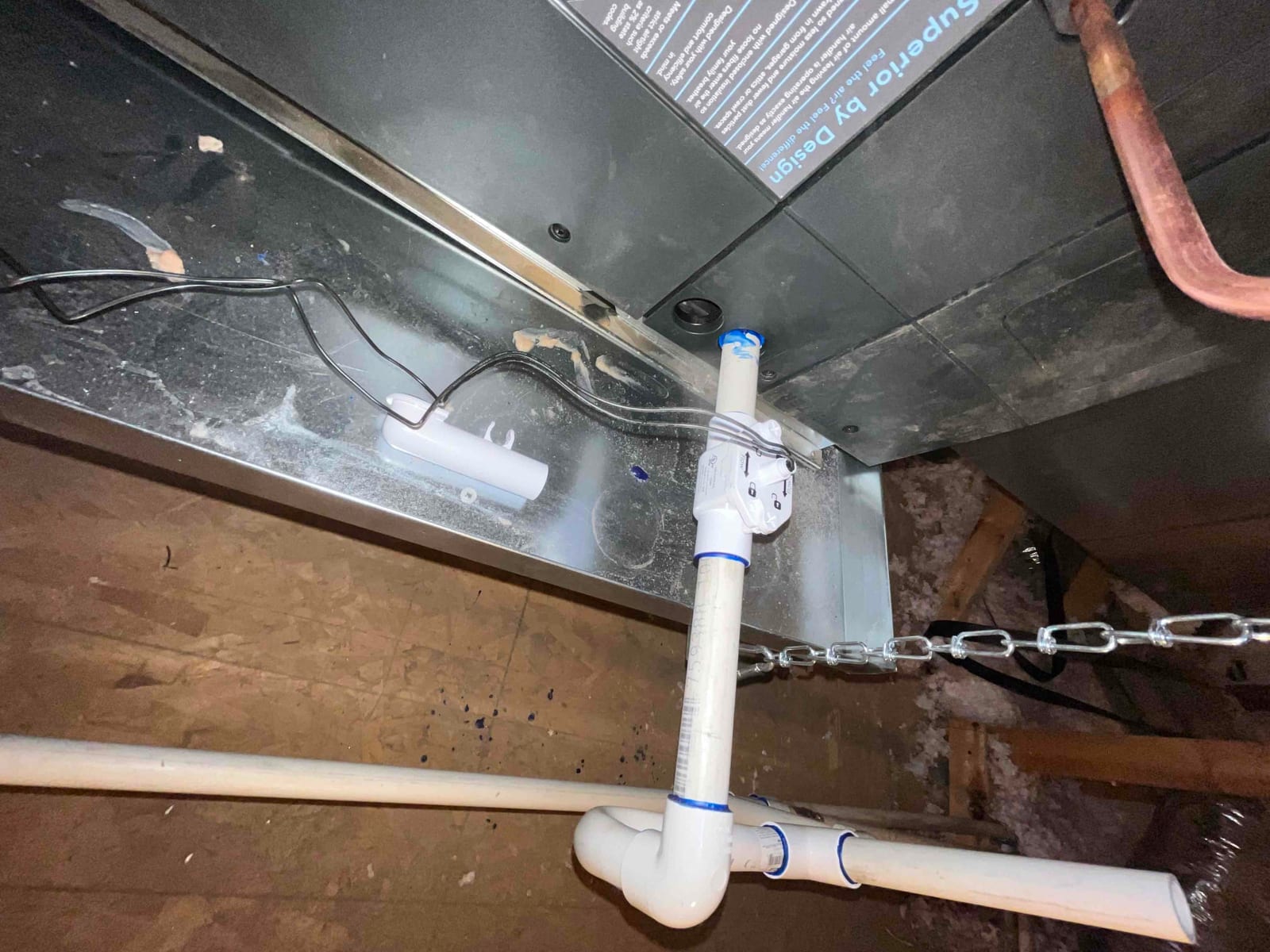 Condensate drain assembly with float switch installed at the air handler, secured with PVC fittings and supported in the attic.