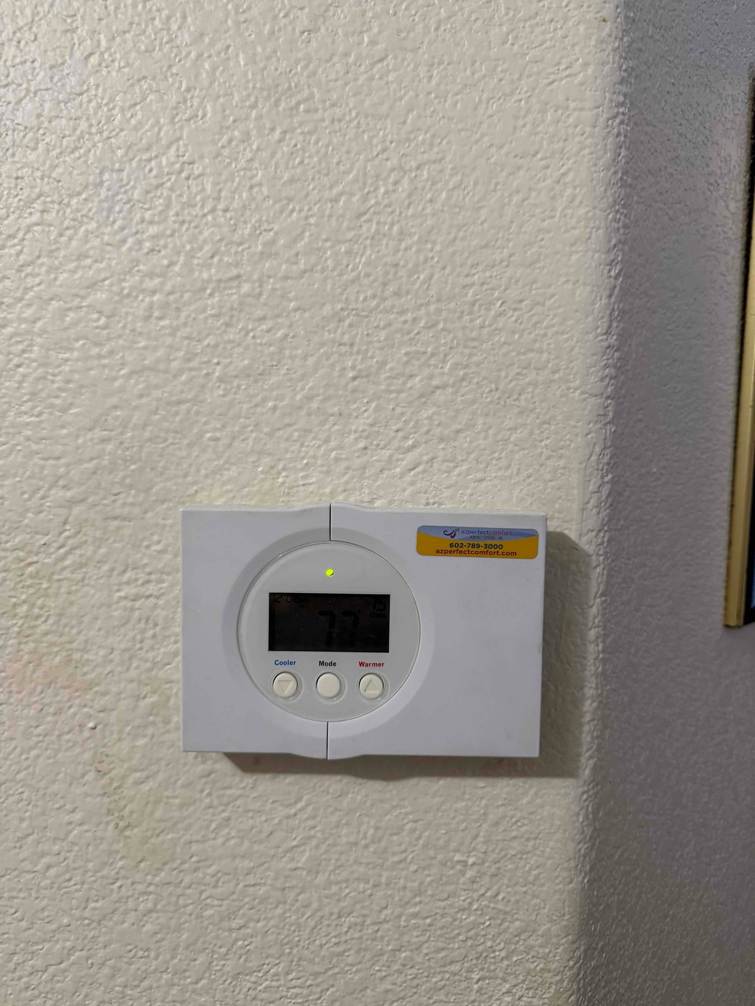 Wall-mounted digital thermostat shows a 77°F setpoint with mode and fan control buttons visible.