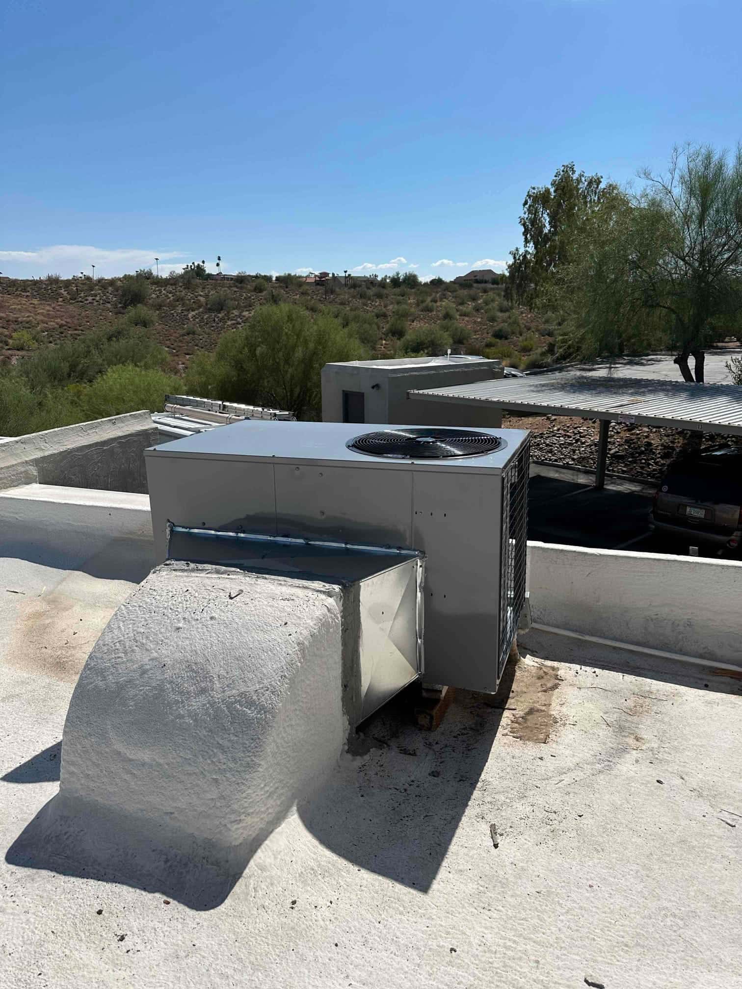 New rooftop packaged heat pump set on curbed roof penetration with sealed sheet metal transition to the duct opening.