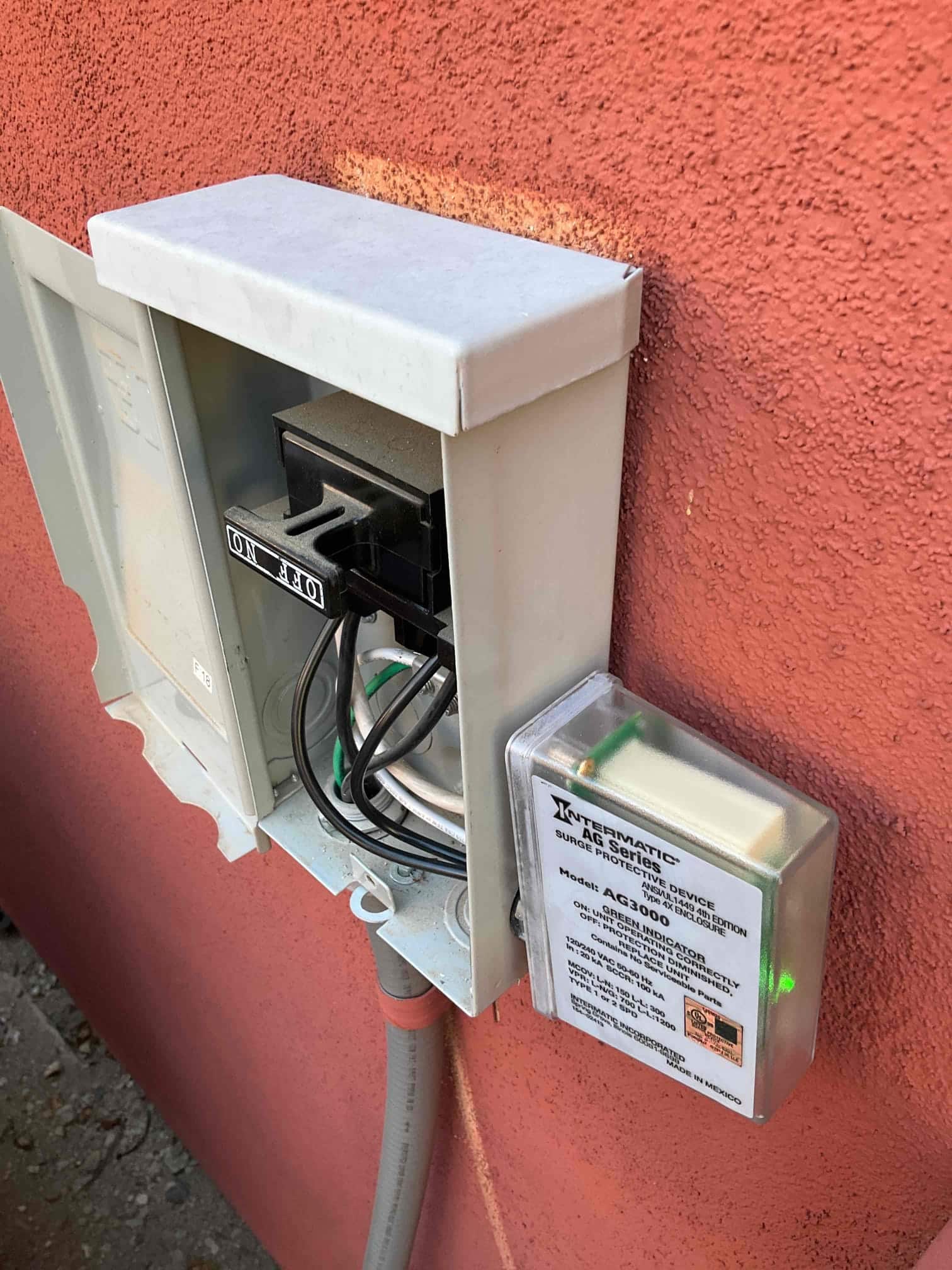 Outdoor disconnect box with pull-out handle in ON position and surge protective device mounted beside it, green indicator illuminated.