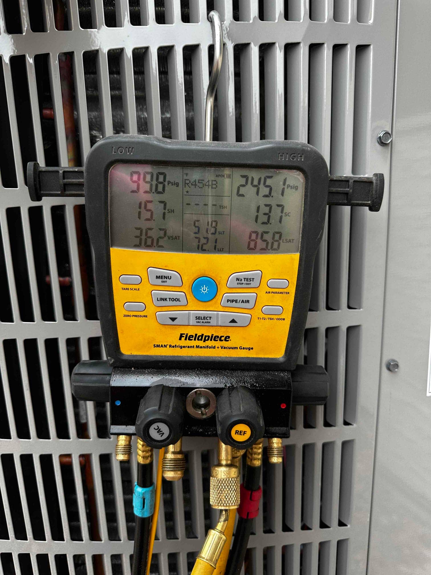 Digital manifold gauges on the condenser show system operating pressures with R-454B selected, documenting active refrigerant commissioning readings.