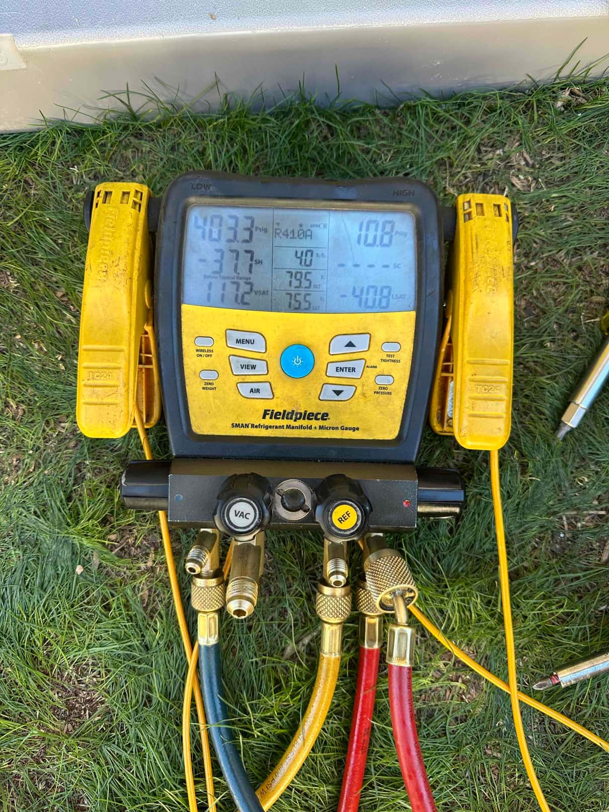 Digital manifold gauges show system operating pressures with R-410A selected, documenting high and low side readings during commissioning.