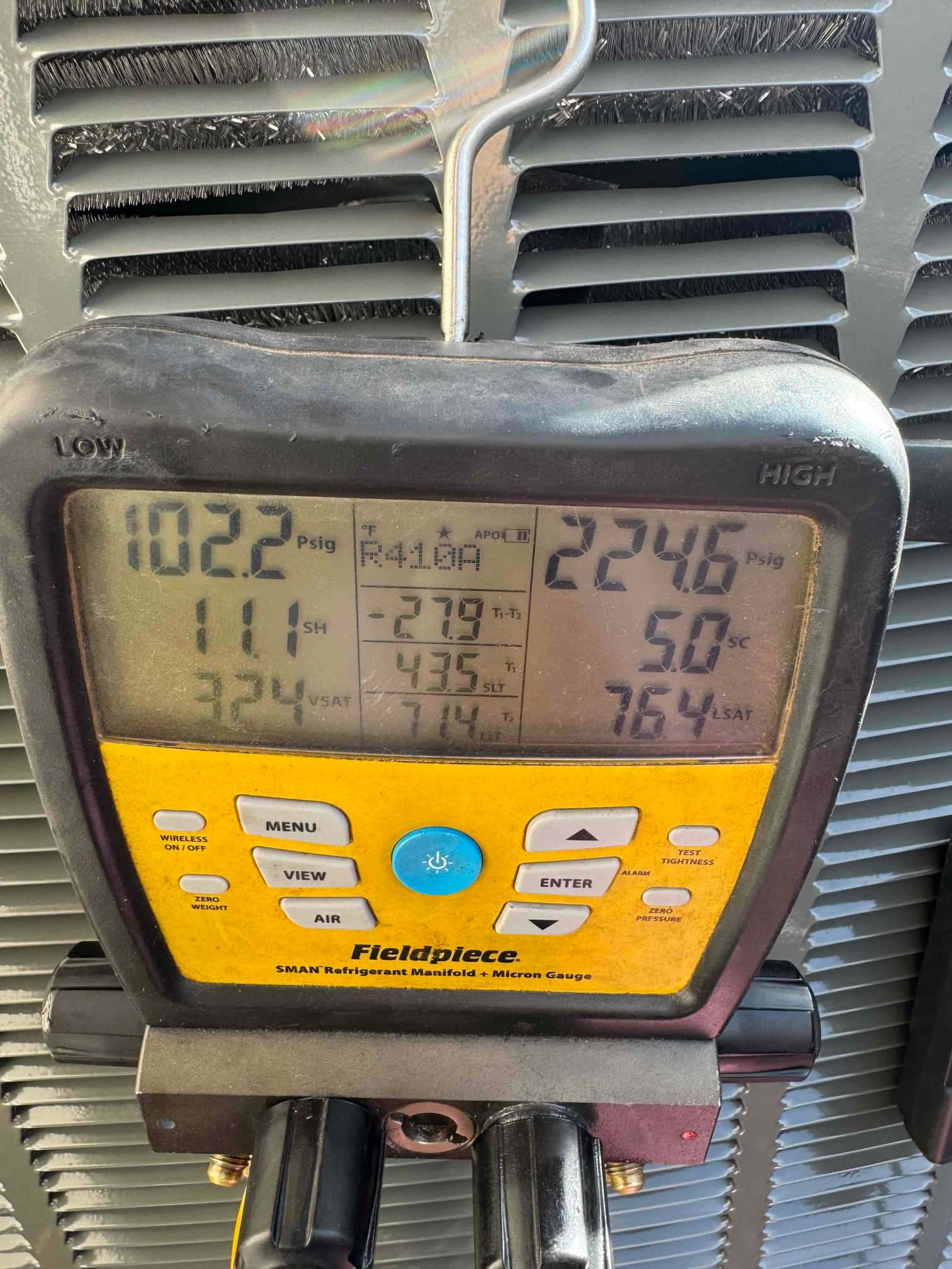 Digital manifold on the outdoor unit shows operating pressures with superheat and subcooling during system commissioning.