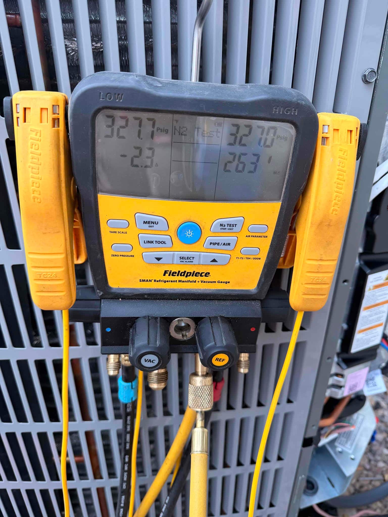 Digital manifold shows equal nitrogen pressure on both sides during the line set pressure test at the outdoor unit.