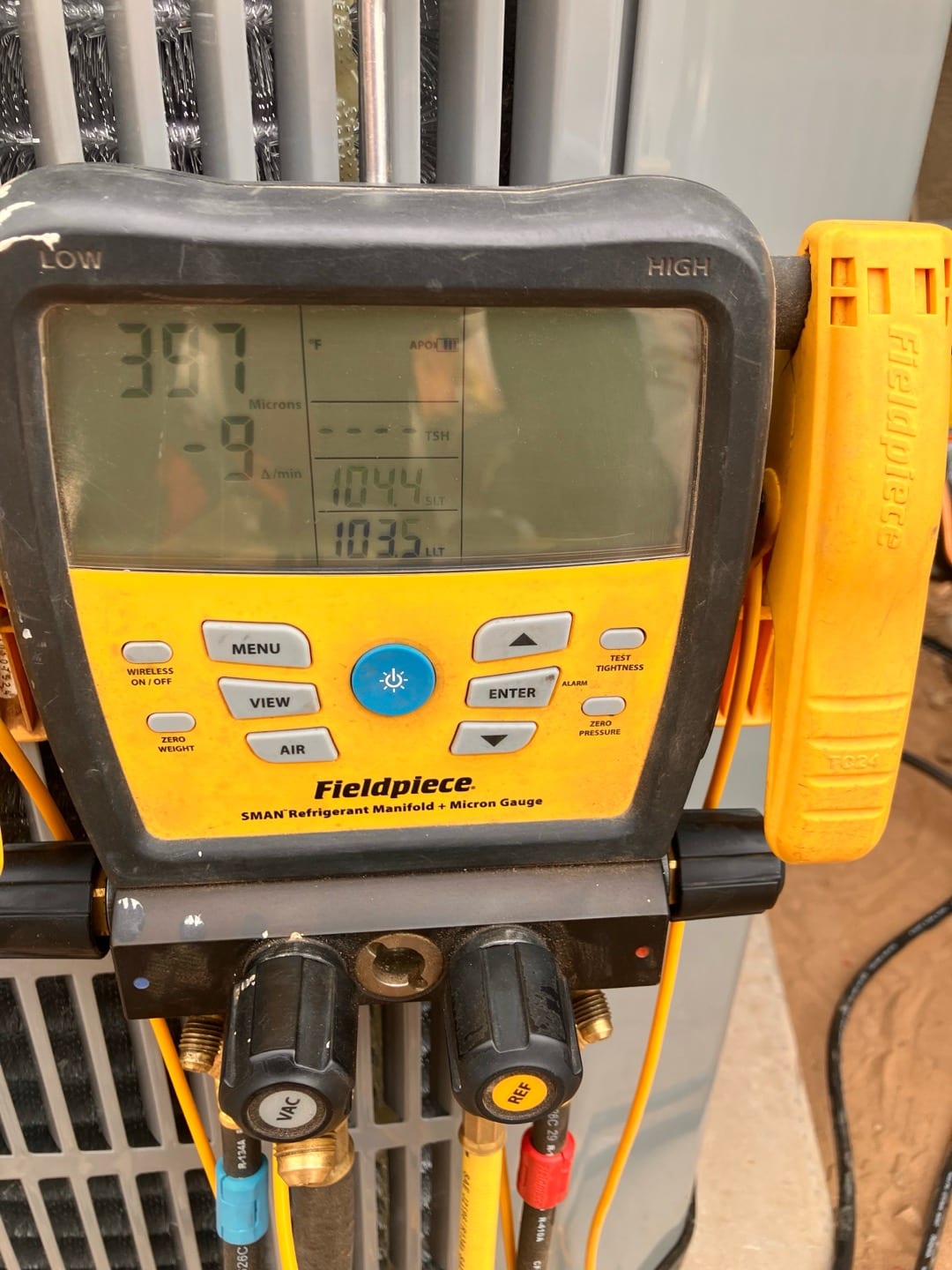 Digital micron gauge on the condenser shows a deep vacuum achieved during system evacuation.