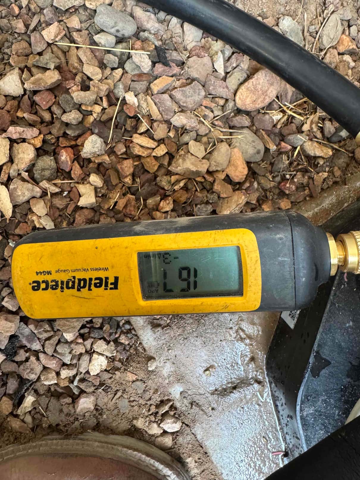 Digital micron gauge shows 167 microns during system evacuation, confirming a deep vacuum before releasing refrigerant.