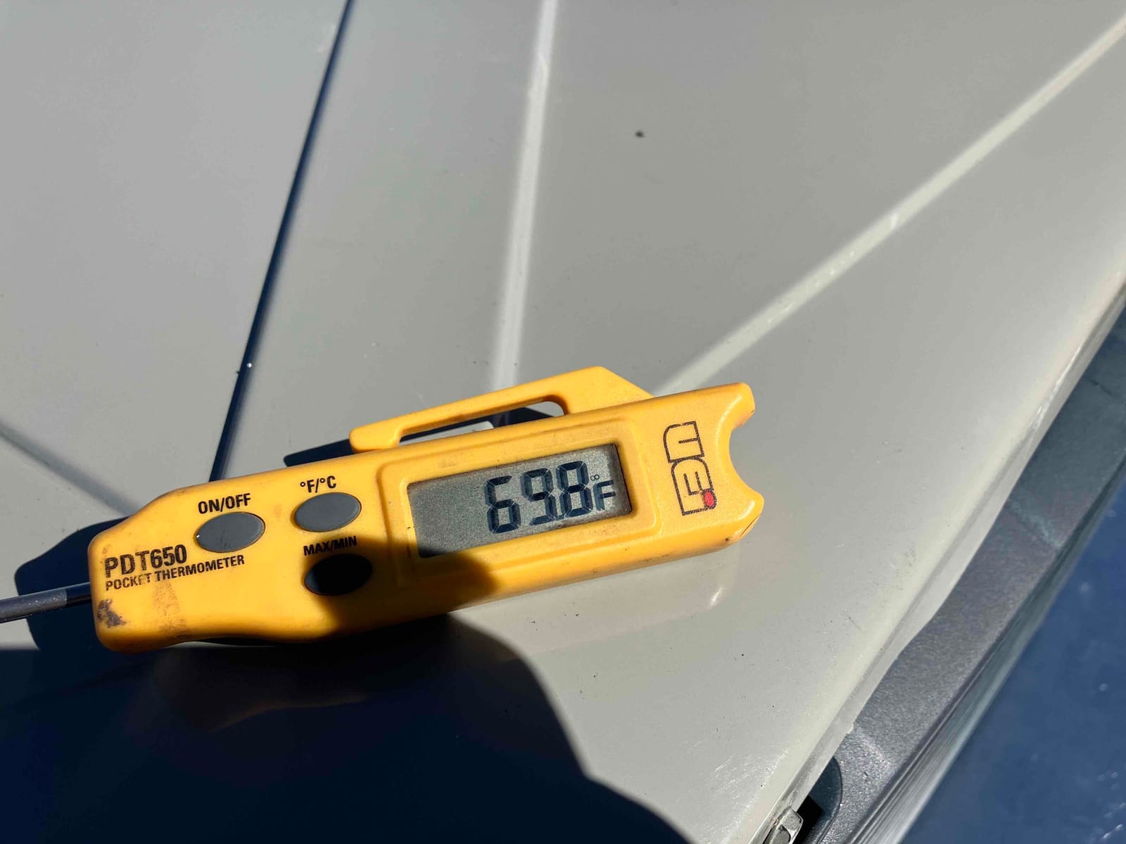 Digital pocket thermometer displays 69.8°F during an air temperature check on the HVAC installation.
