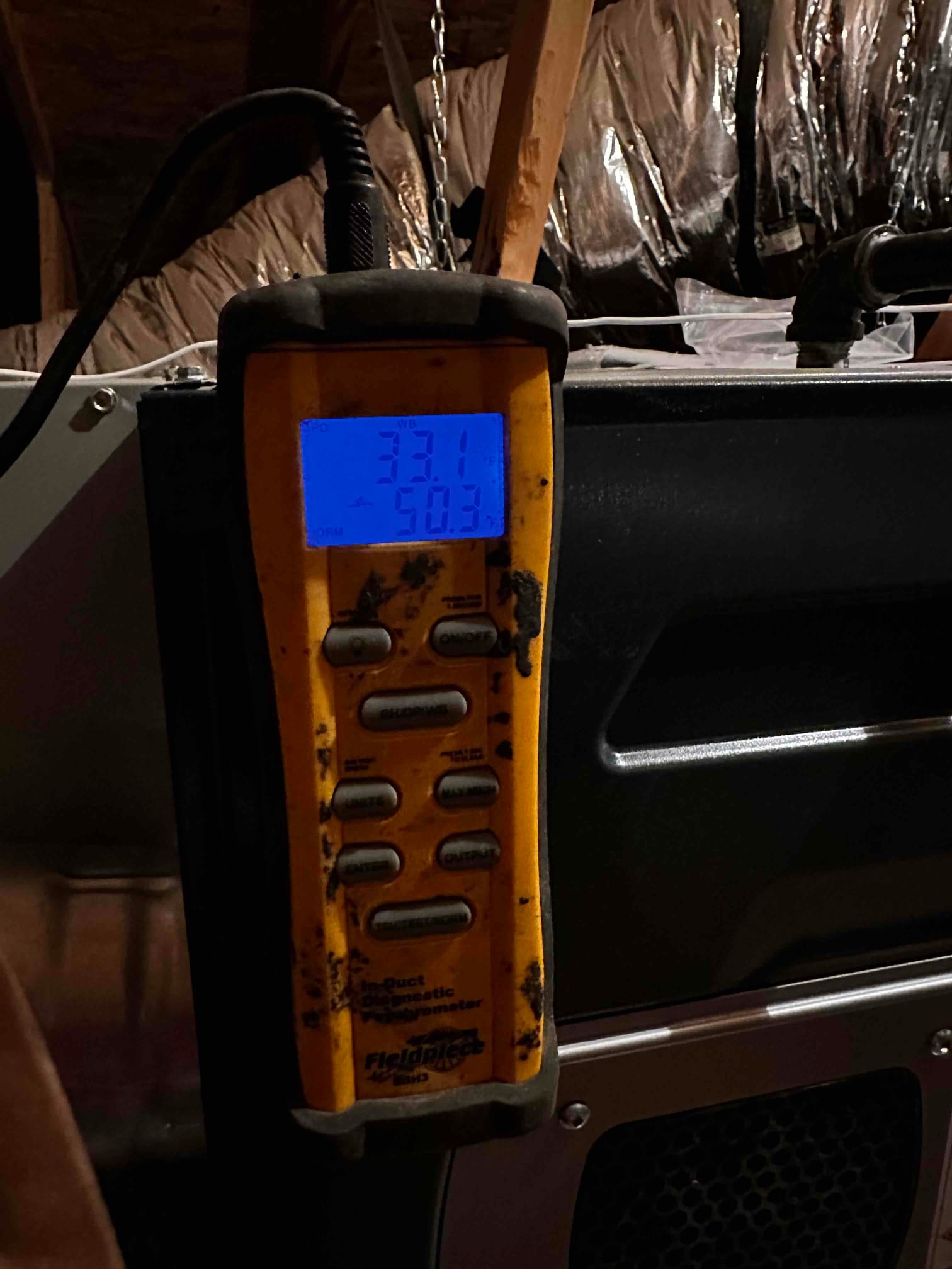 Digital thermometer attached at the air handler shows supply air temperature readings on the illuminated display.