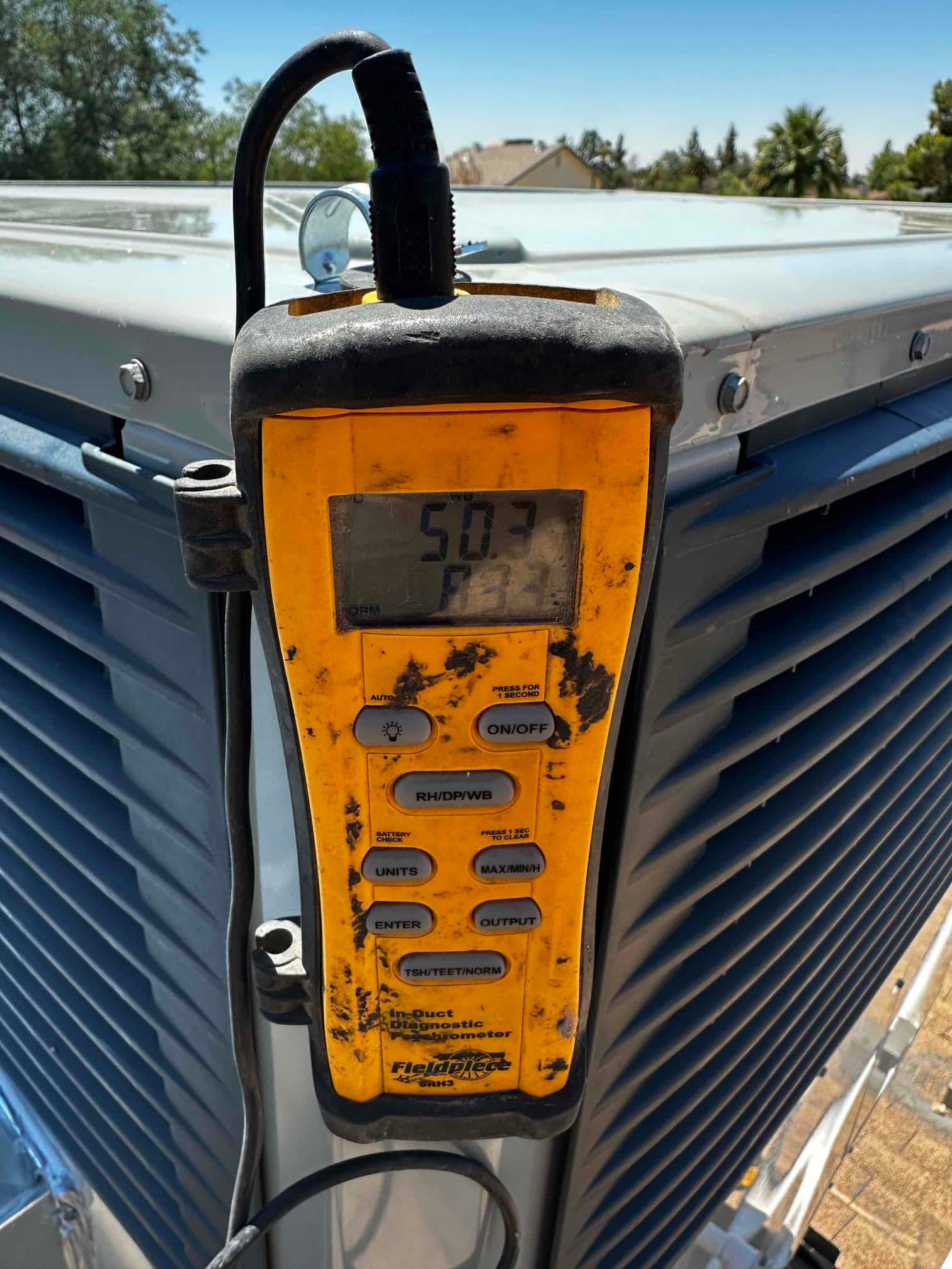 Digital thermometer attached at the outdoor unit shows an air temperature reading of 50.3 degrees Fahrenheit during commissioning.