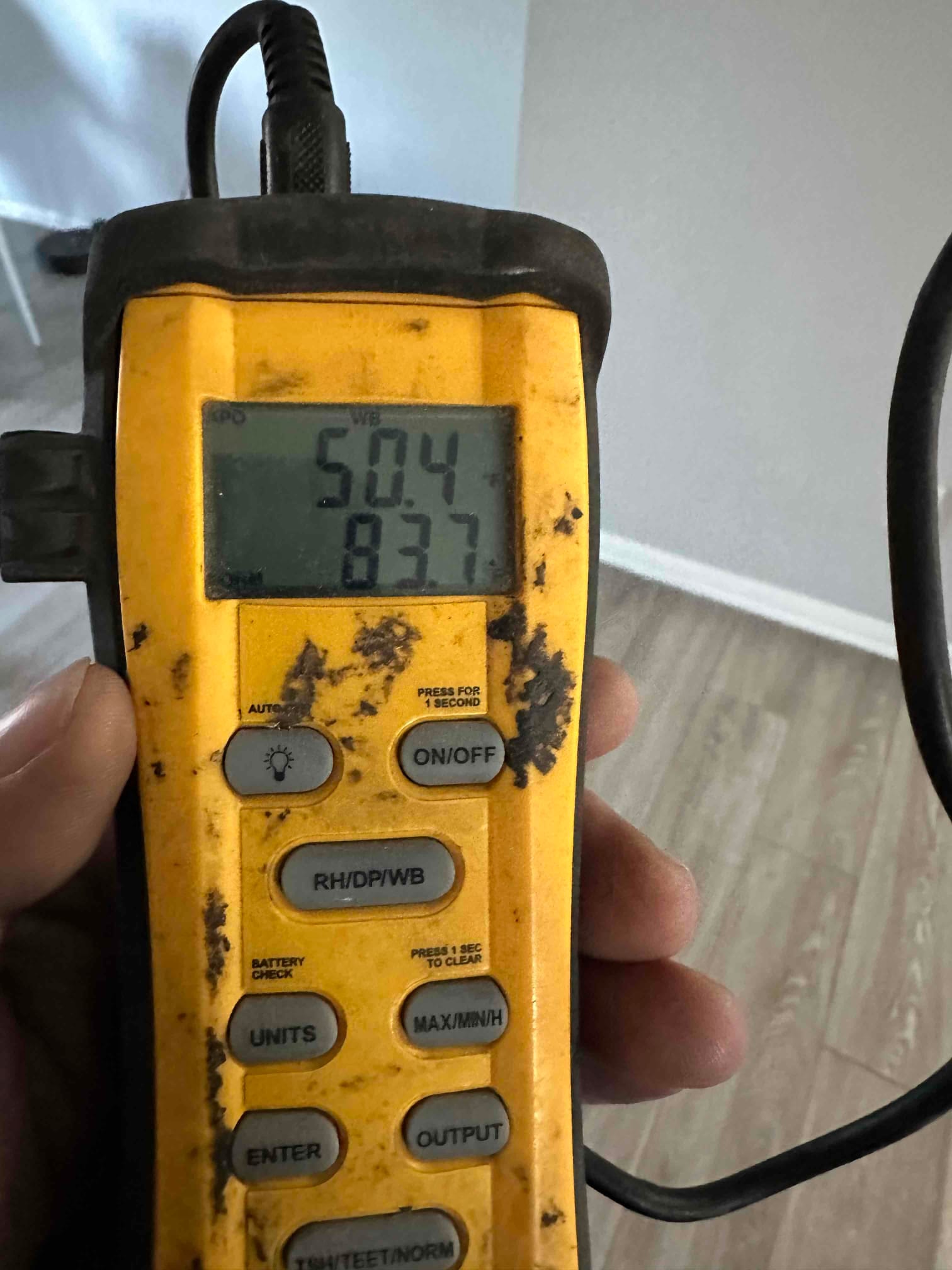 Digital thermometer displays 50.4 degrees and 83.7 degrees during air temperature checks on the newly installed system.