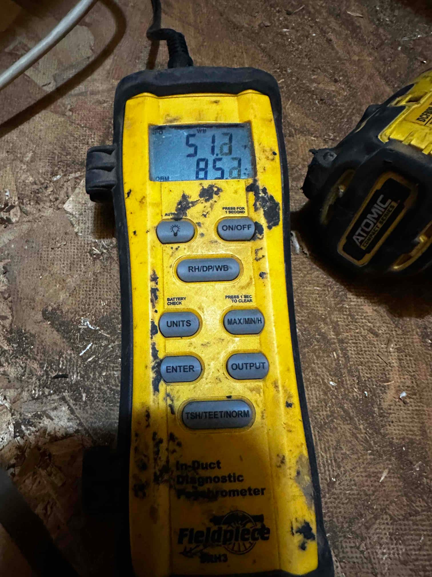 Digital thermometer displays 51.2 degrees Fahrenheit, documenting cold supply air temperature during system commissioning.