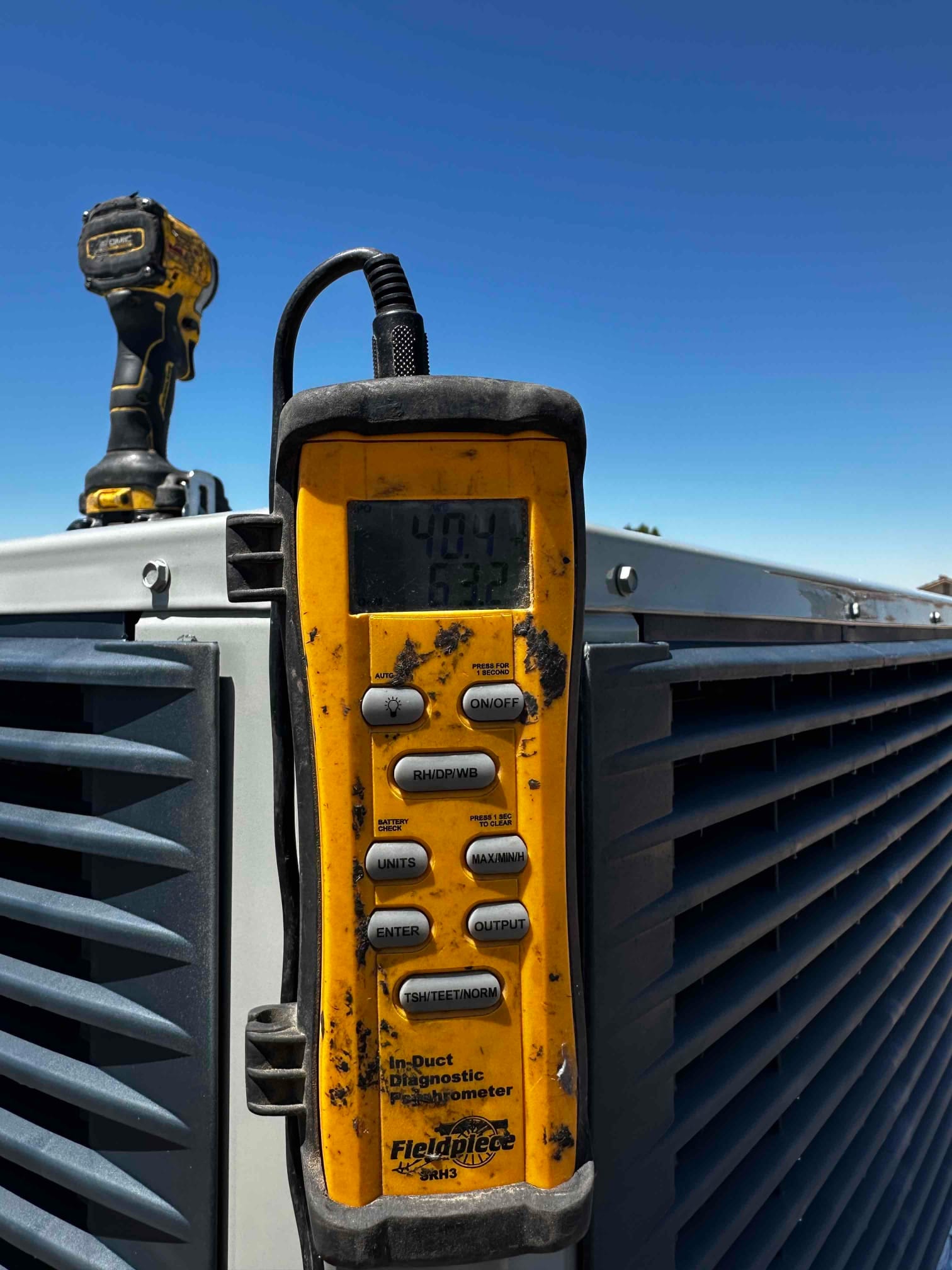 Digital thermometer at the outdoor unit shows air temperature readings on the display during commissioning checks.