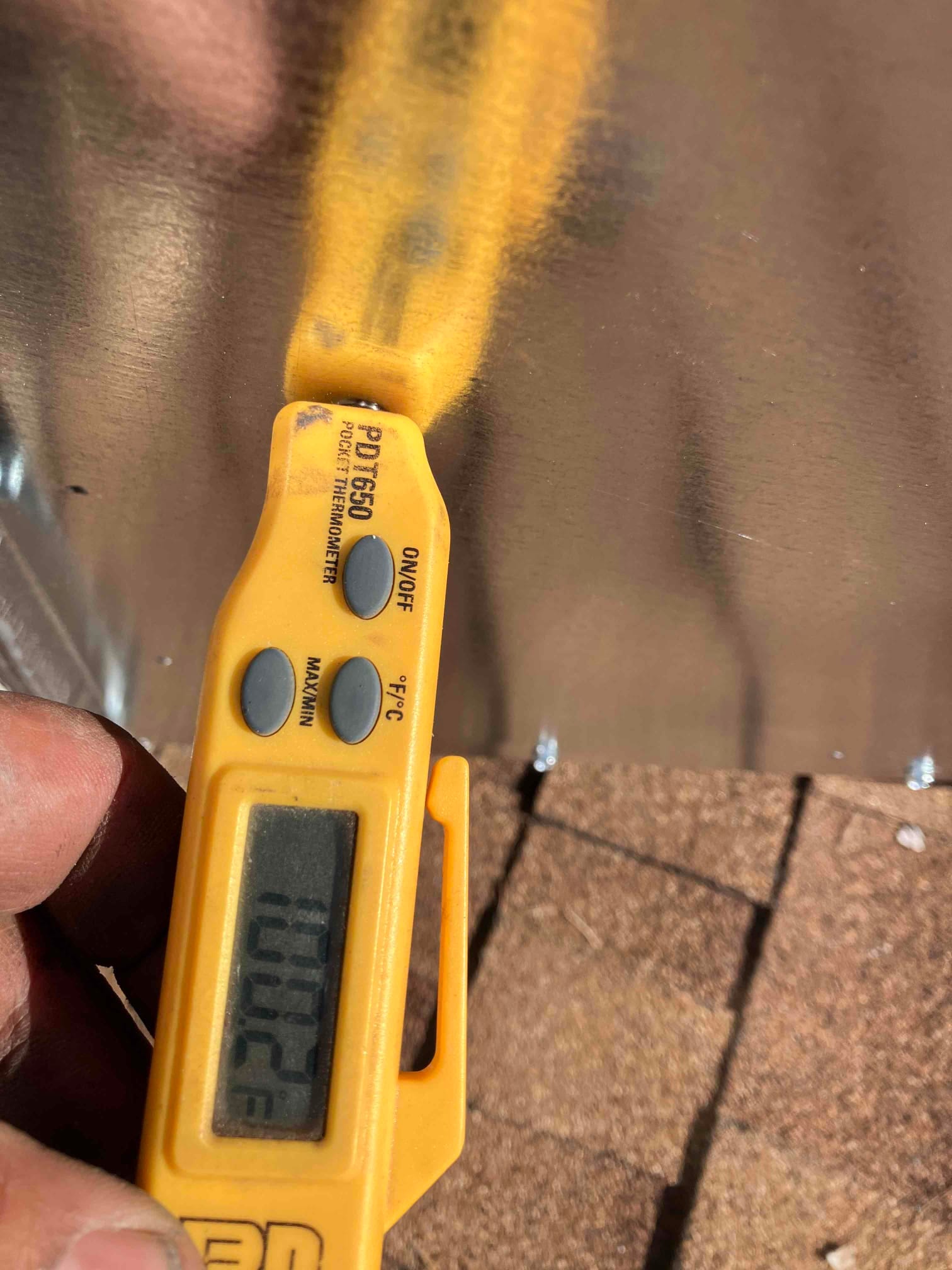 Digital thermometer shows 100.2°F while measuring air temperature during HVAC commissioning.