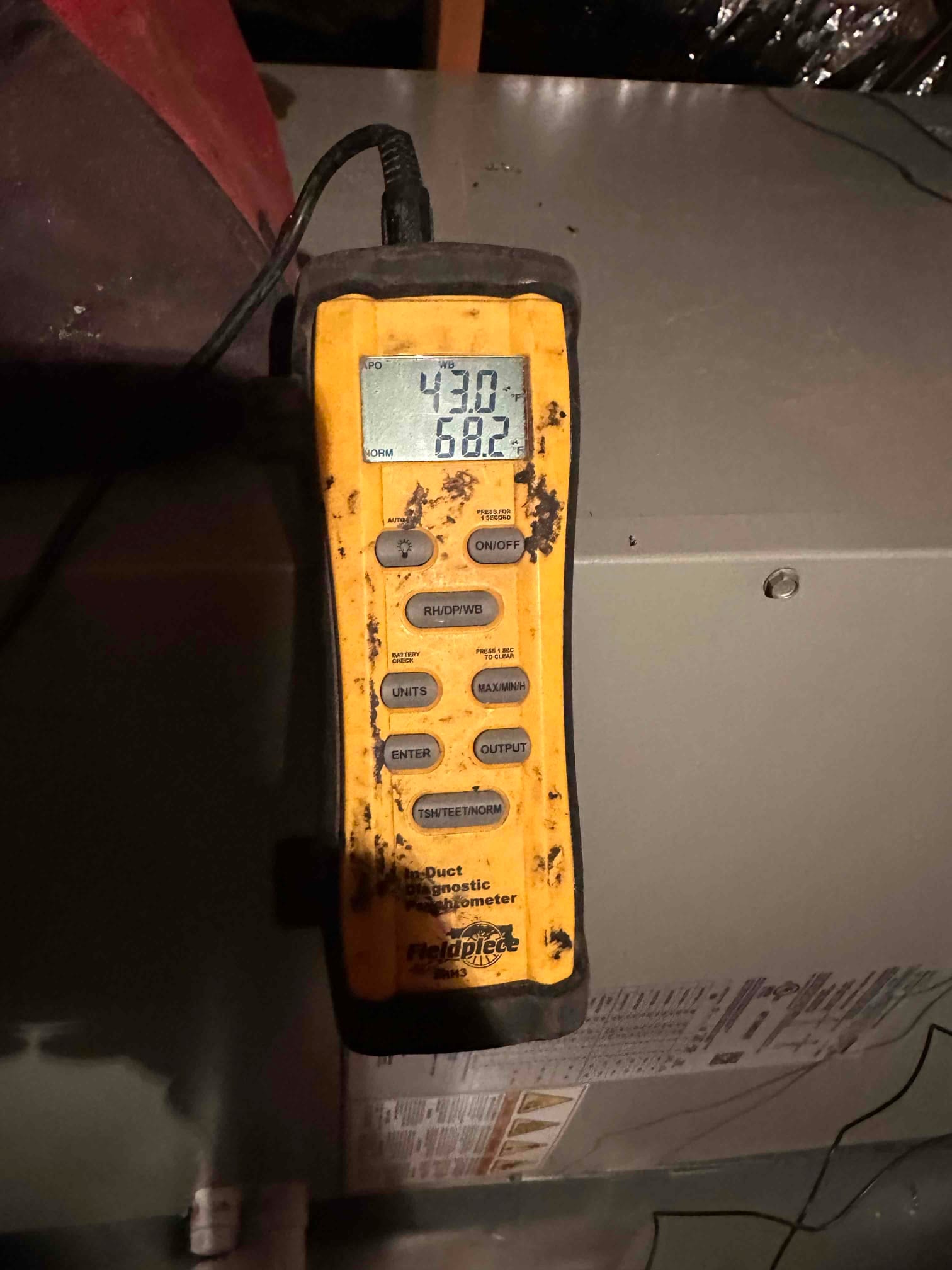 Digital thermometer shows 43.0 degrees on the upper line and 68.2 degrees on the lower line during air measurements at the air handler.