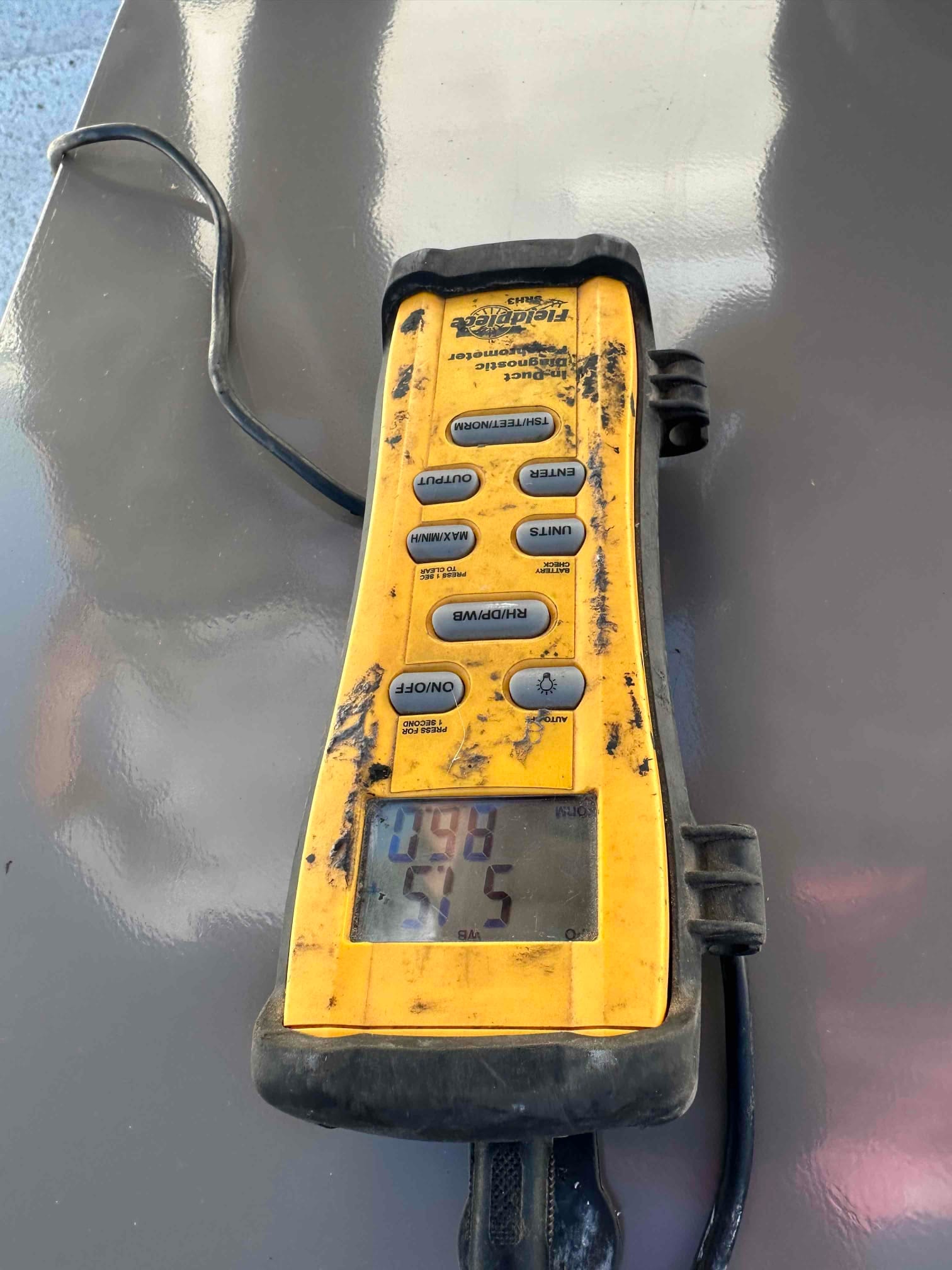 Digital thermometer shows 51.5 degrees Fahrenheit, documenting cold supply air temperature during system commissioning.