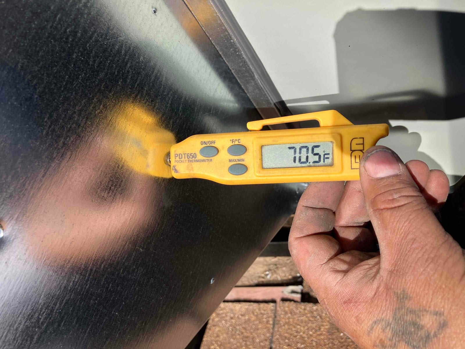 Digital thermometer shows 70.5°F while measuring air temperature during HVAC commissioning at the installation site.