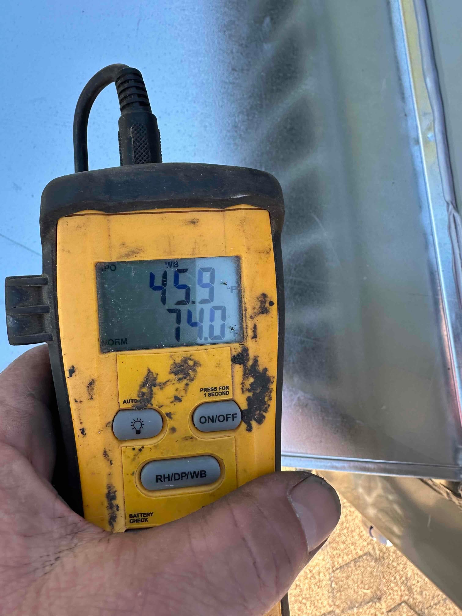 Digital thermometer shows 74.0 degrees while checking air temperature during HVAC system commissioning.