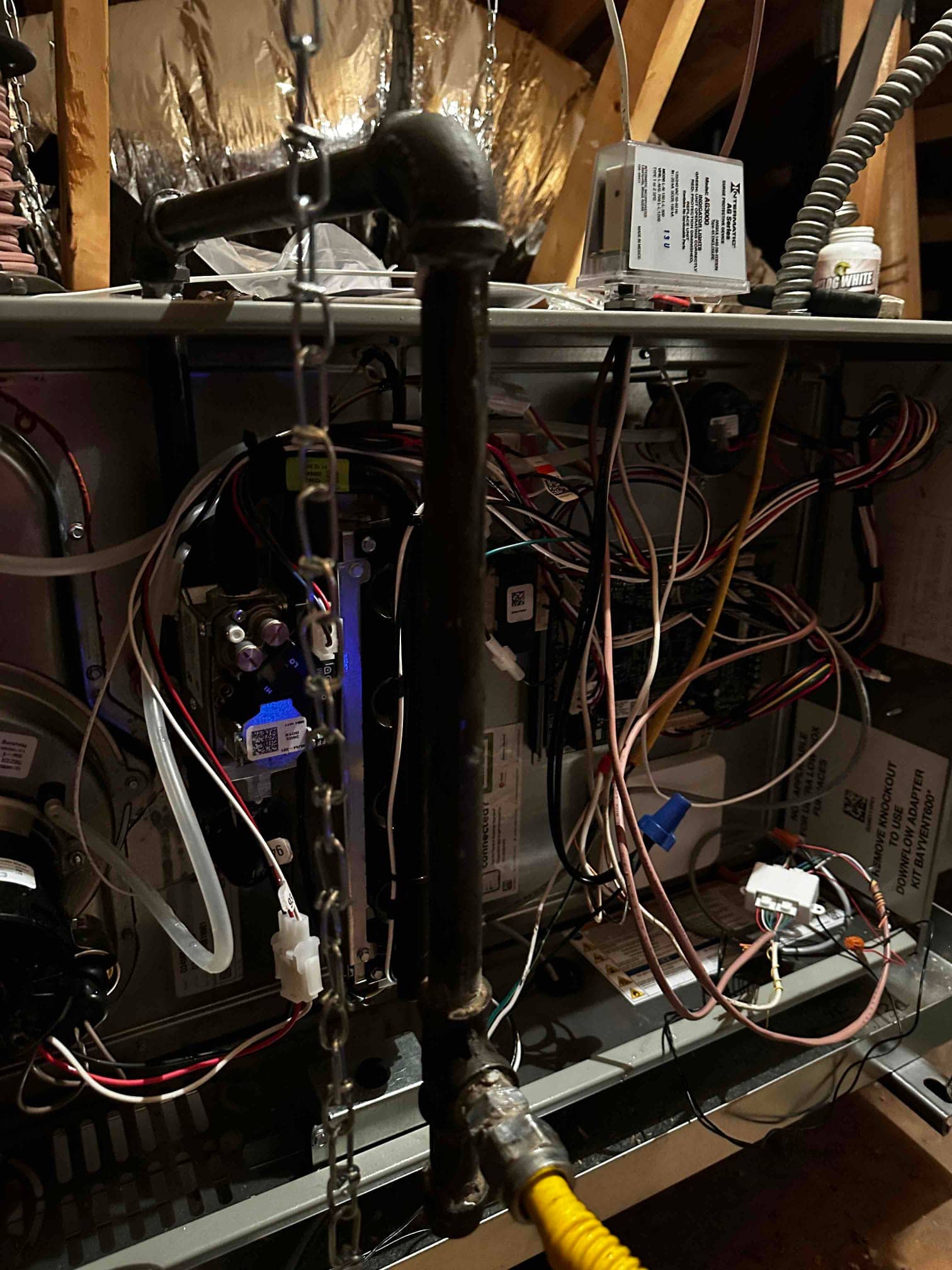 Furnace and air handler installed in attic with gas piping, control wiring, and condensate tubing routed inside the open cabinet.