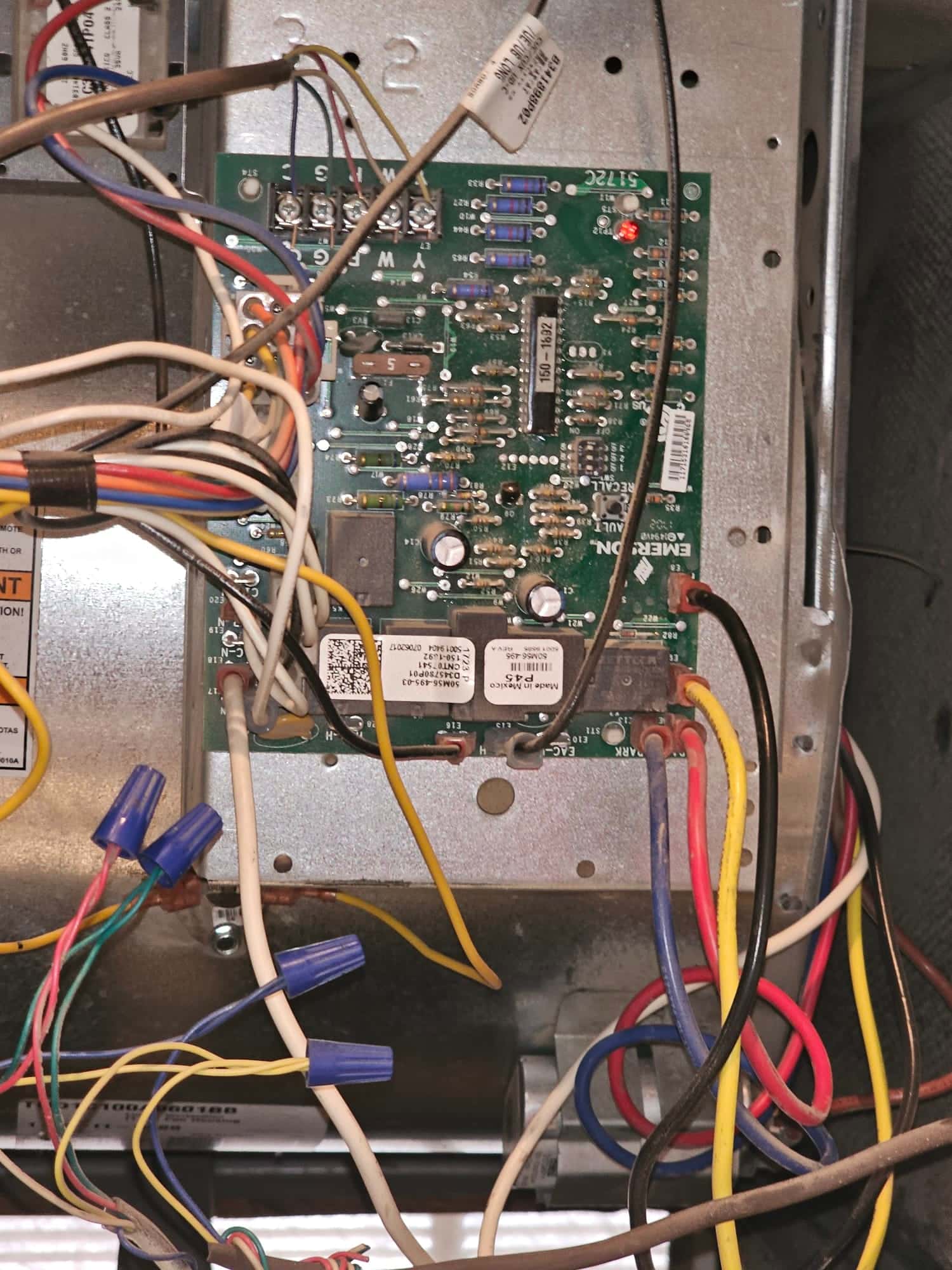 Furnace control board inside the air handler, showing wired terminals, relays, and multiple conductors joined with blue wire nuts.