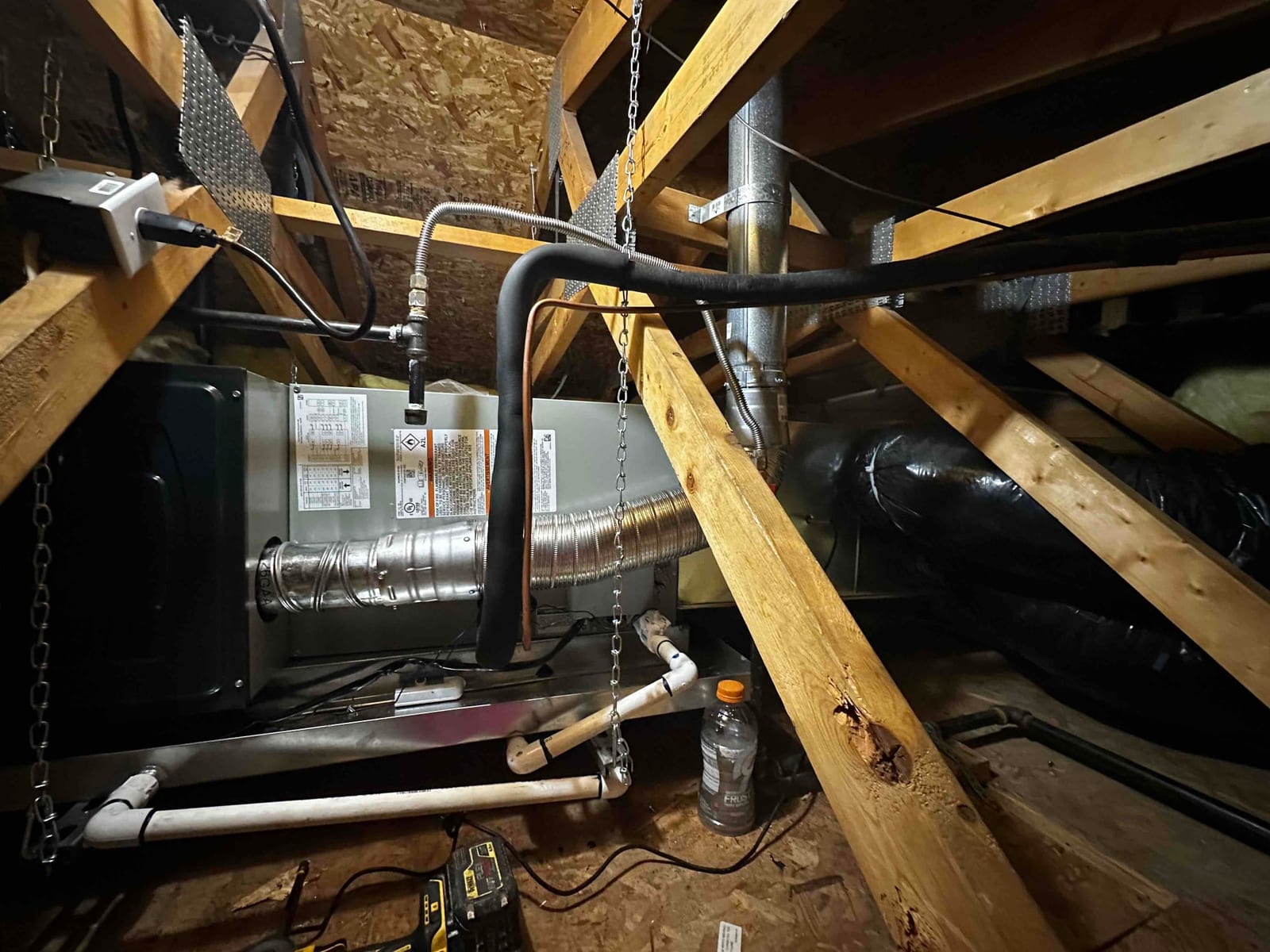 Horizontal attic air handler suspended on hangers with insulated refrigerant lines, metal supply plenum, PVC condensate drain, and flexible duct connections.