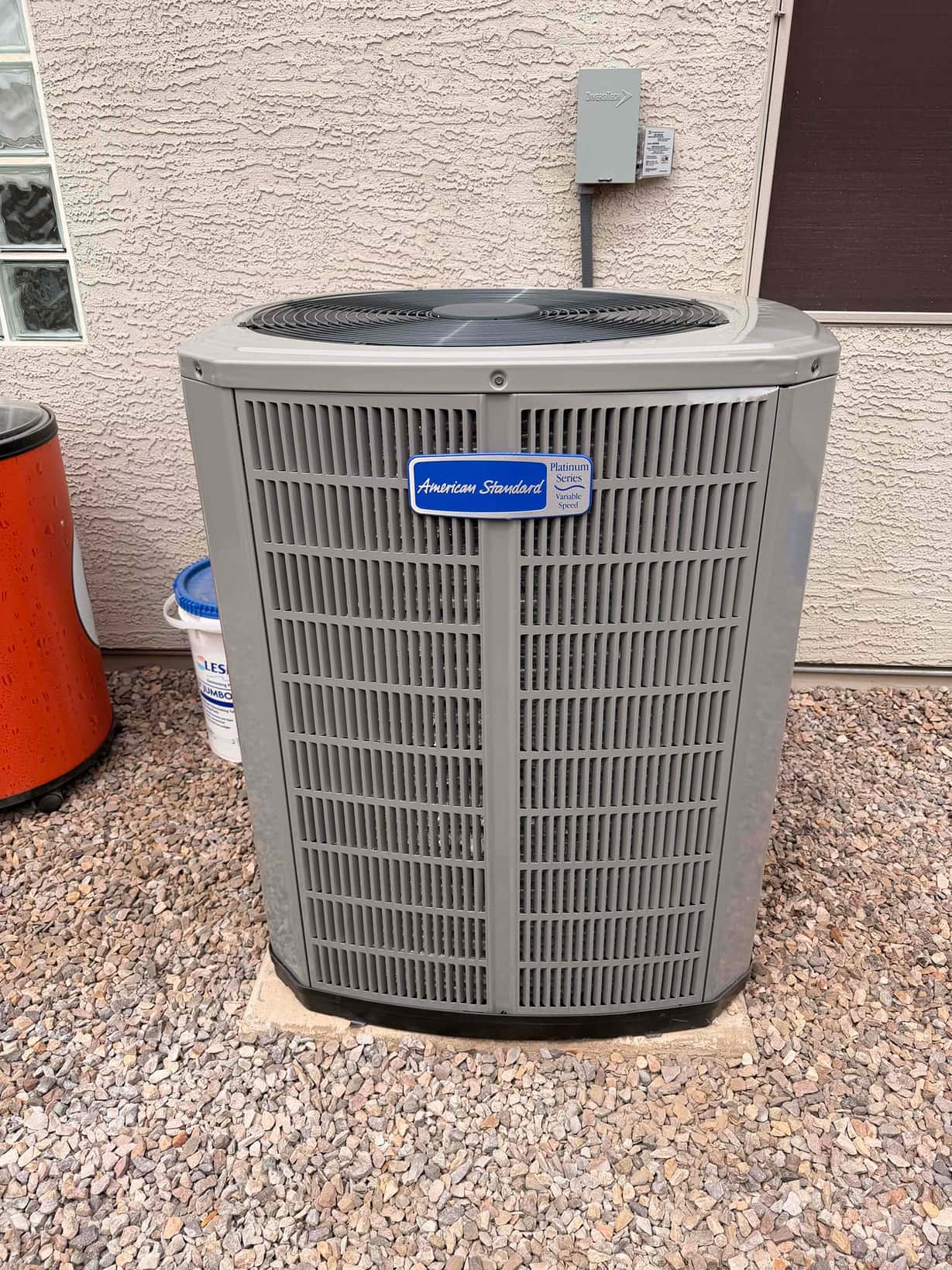 New outdoor condenser set on a level pad with disconnect box mounted on the wall and sealed line entry.