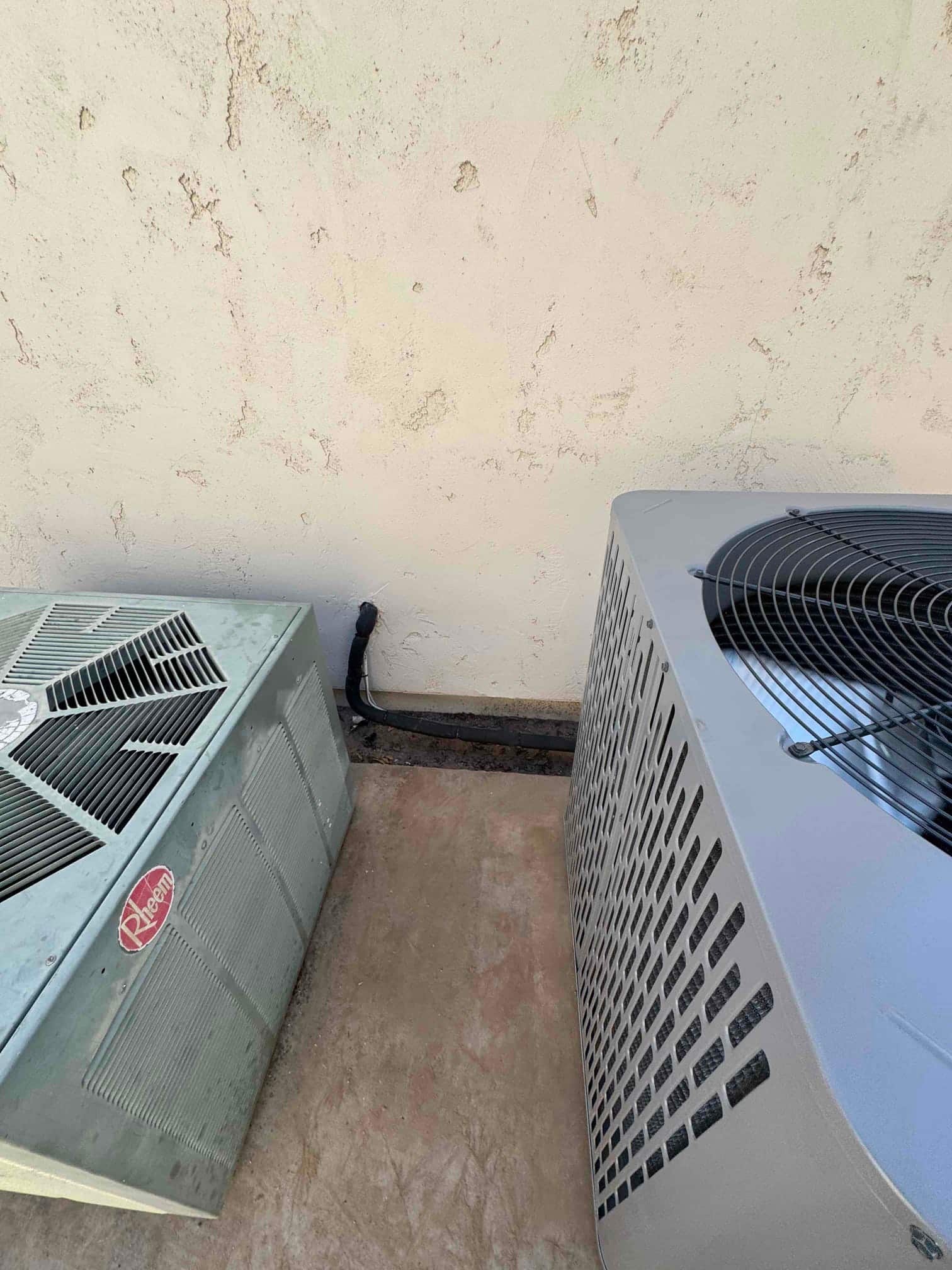 New outdoor condenser set on pad beside old unit, with insulated refrigerant line set routed along the wall.
