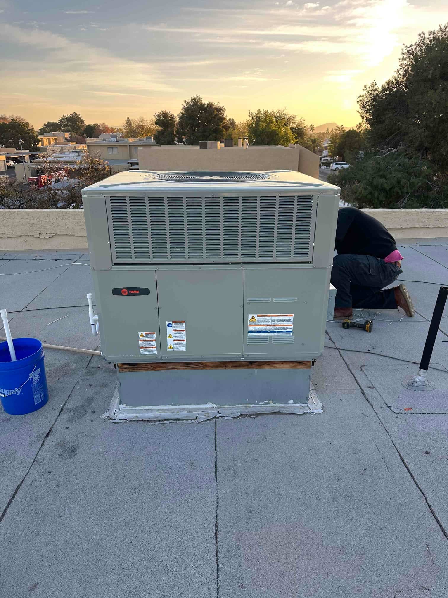 New packaged rooftop HVAC unit set on a curb with sealed flashing and exterior labels visible during installation.