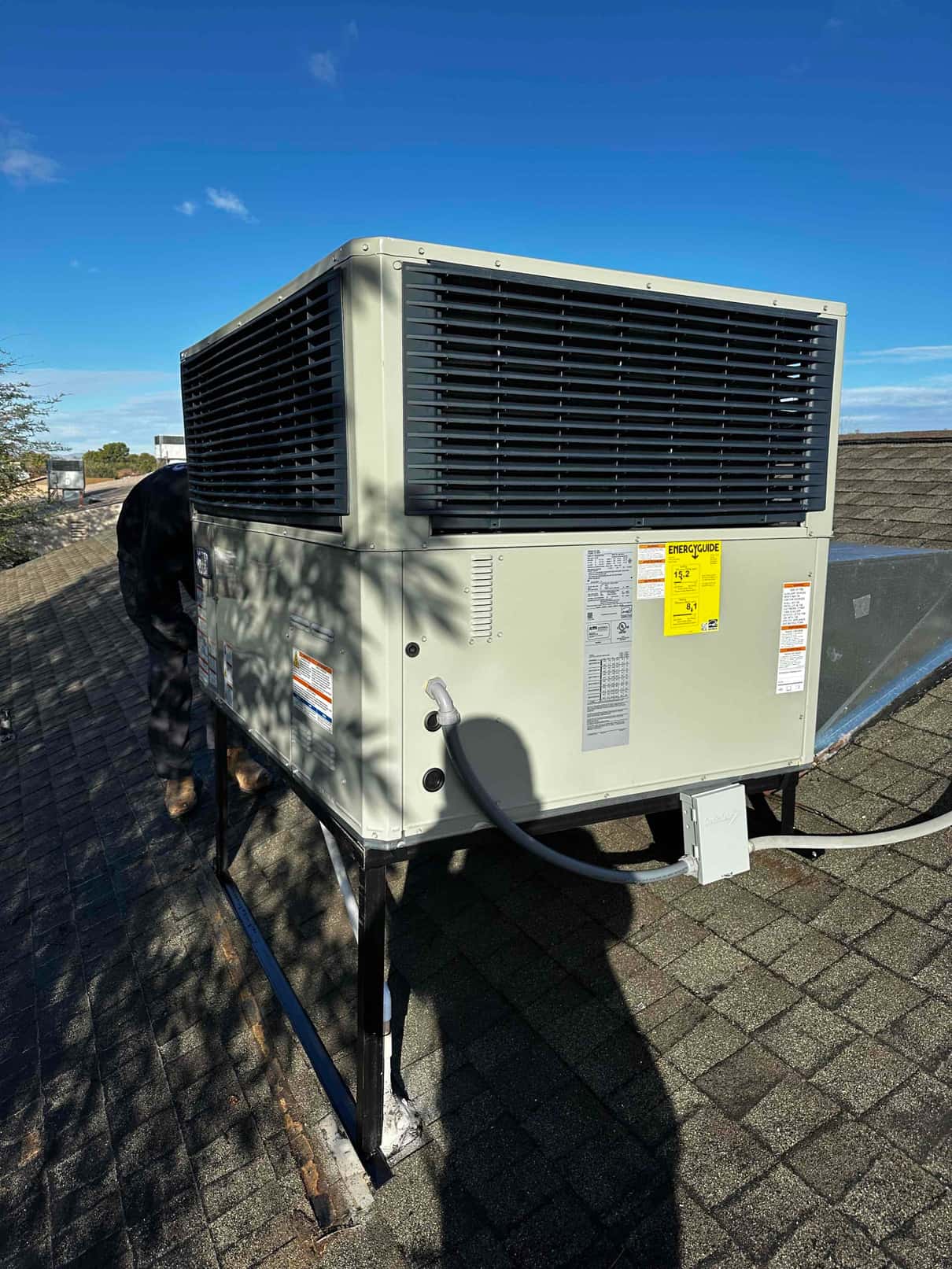 New rooftop packaged HVAC unit installed on a metal stand with electrical disconnect and condensate drain connected.
