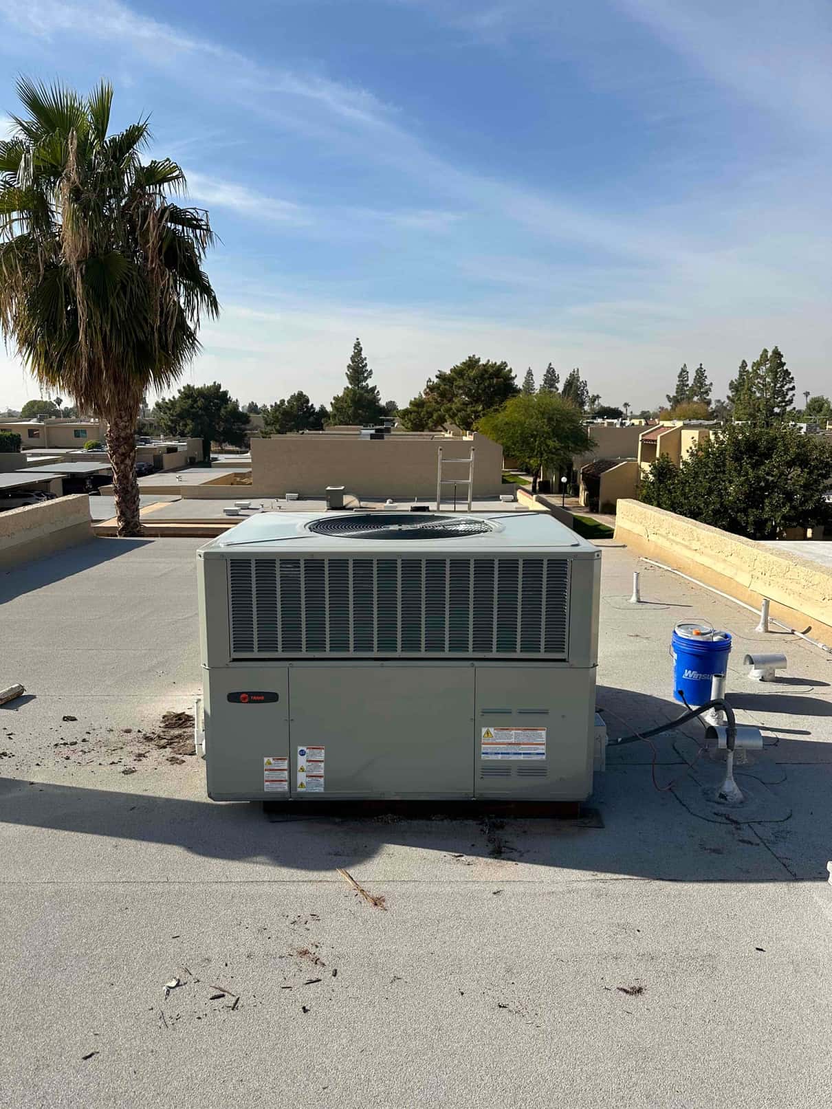 New rooftop packaged HVAC unit set on curb with electrical whip and roof penetrations visible around the installation area.