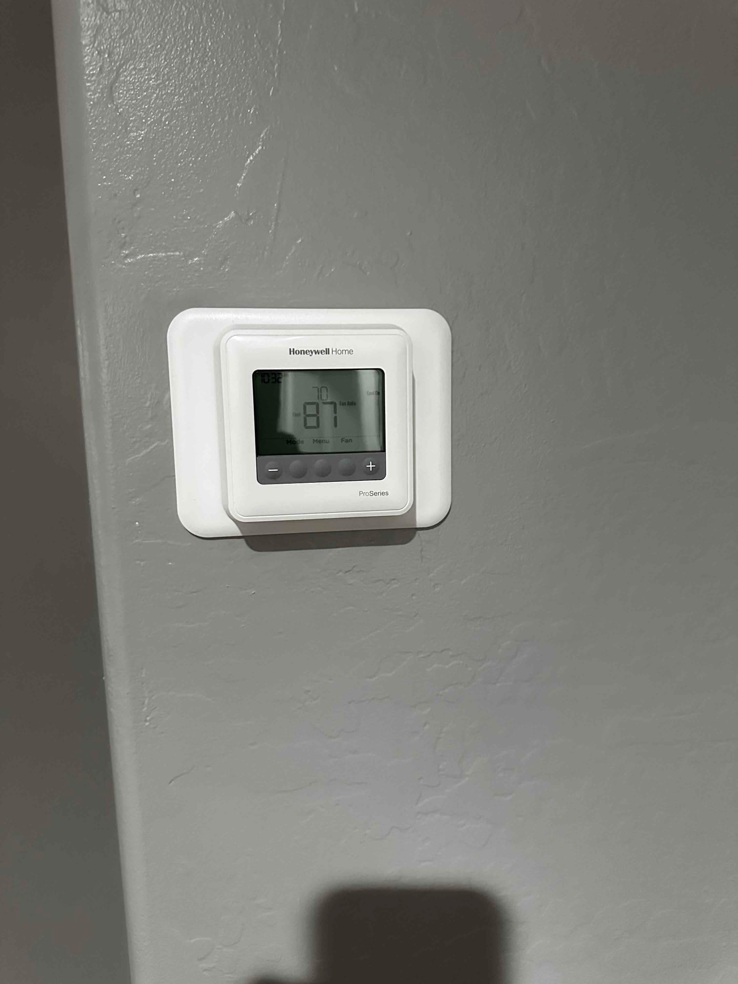 New wall-mounted thermostat installed and powered, displaying room temperature and control buttons for mode and fan.