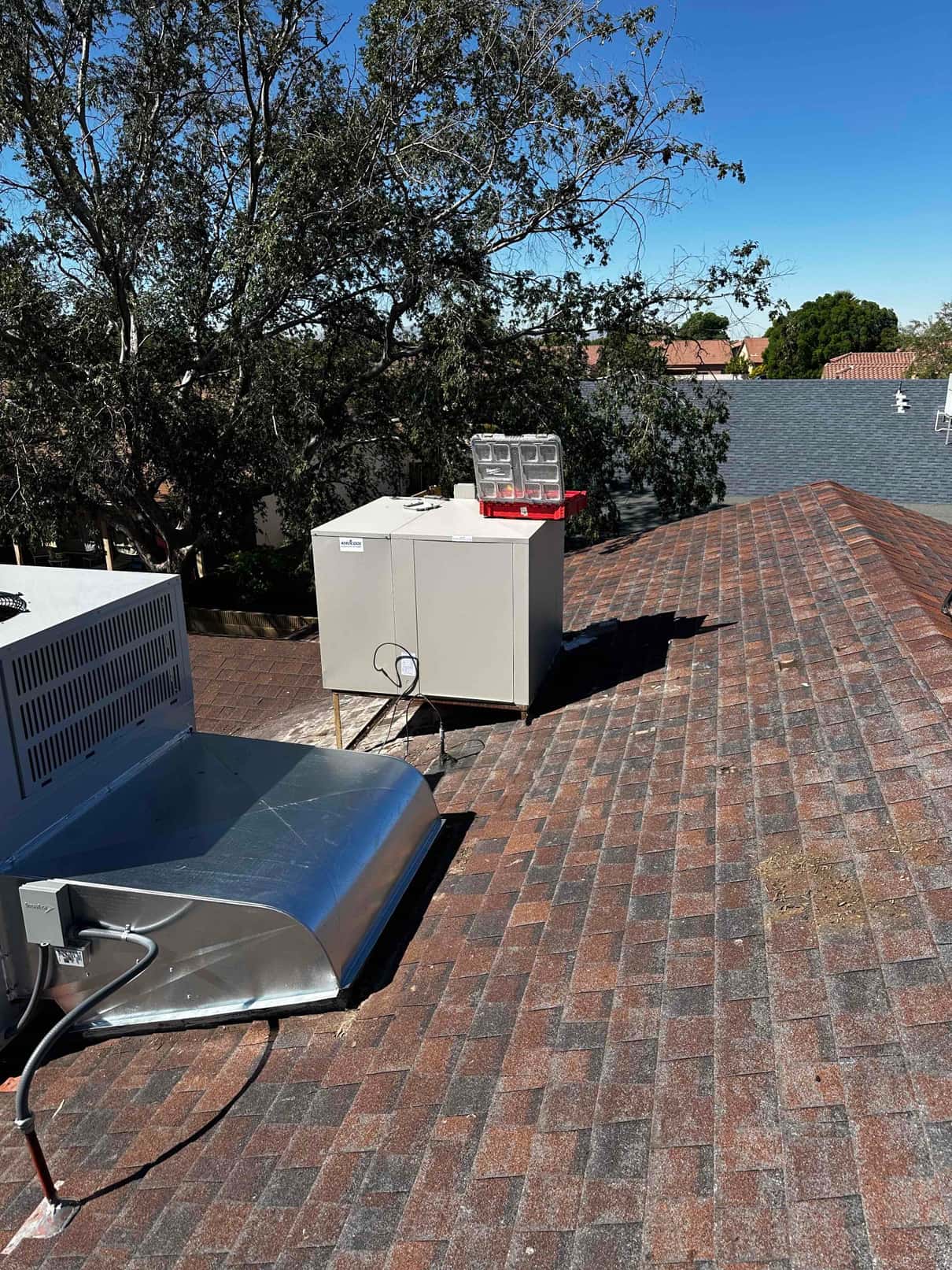 Rooftop HVAC installation showing new equipment set on shingle roof with electrical disconnect and sealed curb flashing.
