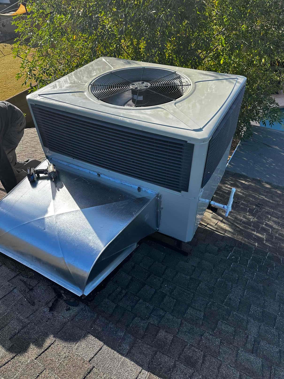 Rooftop packaged heat pump installed with new sheet-metal curb adaptor and connected condensate drain piping.