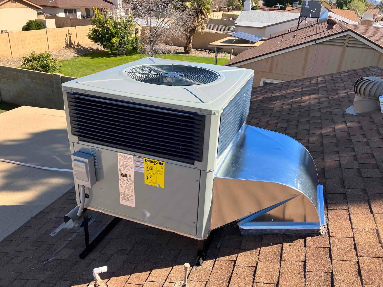 Rooftop packaged HVAC unit newly installed on curb with sealed sheet-metal supply/return transition and exterior disconnect box.