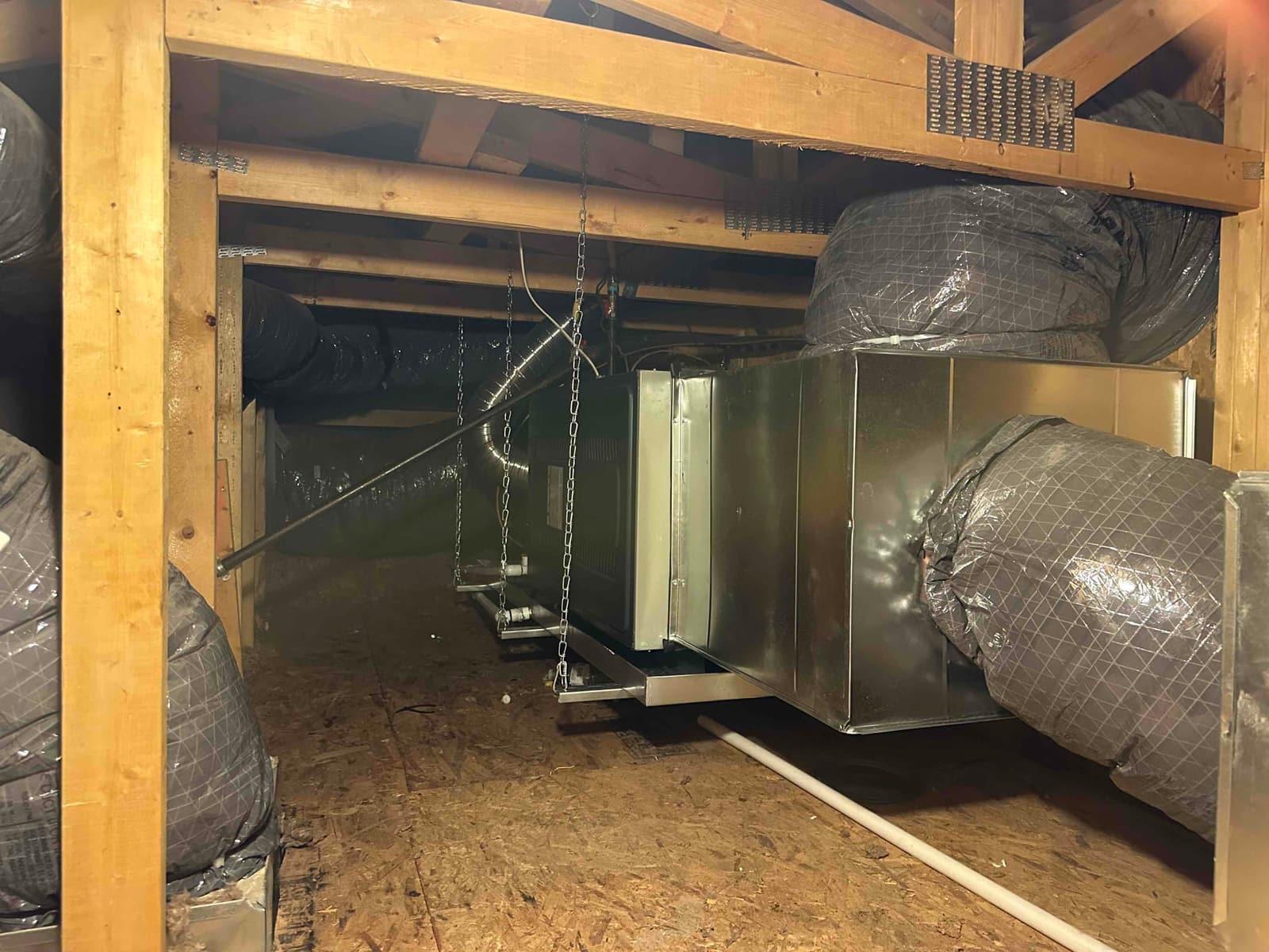 Suspended air handler with new metal plenum and insulated flex ducts installed in attic, supported by chains and hangers.