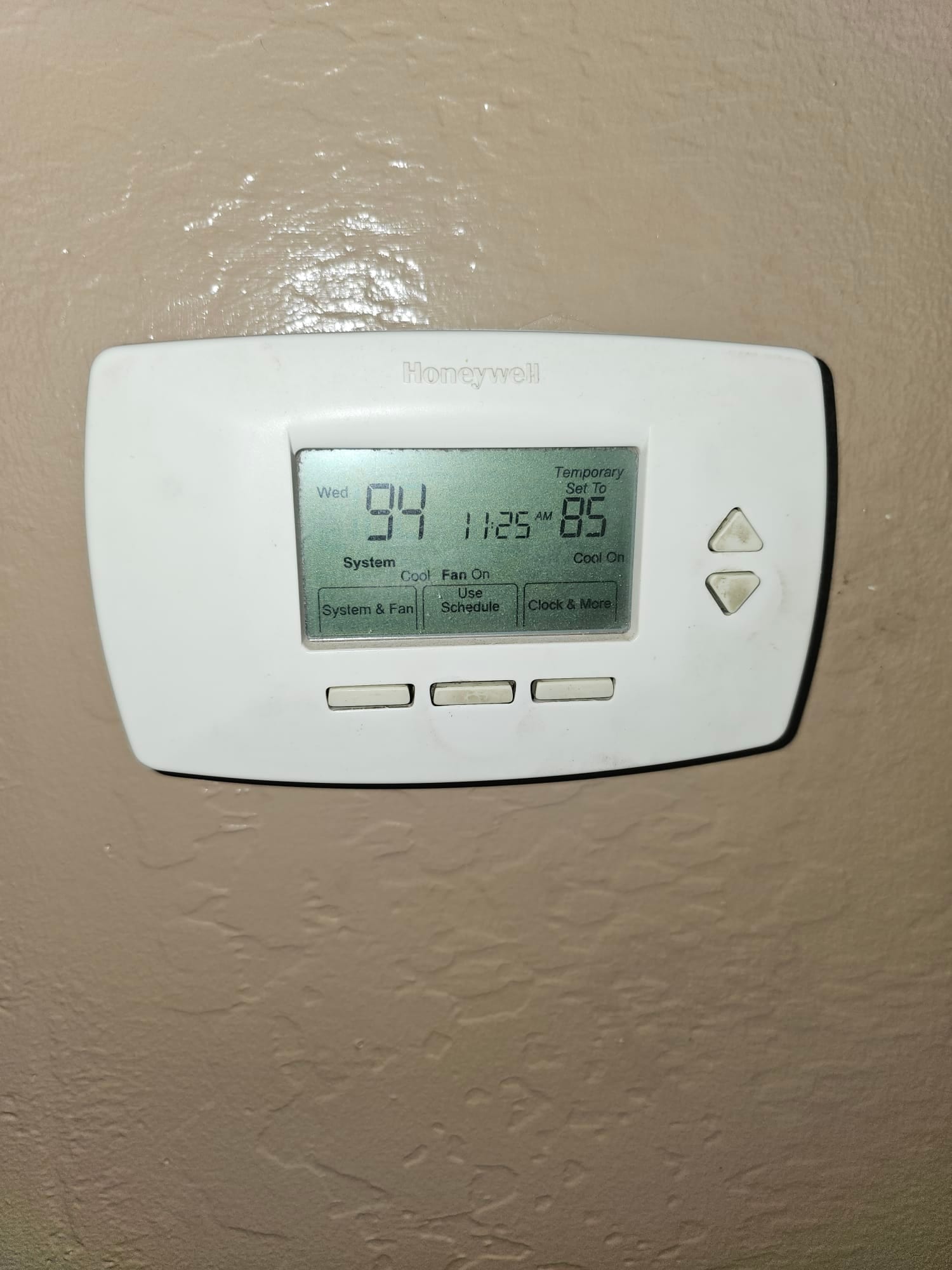 Wall-mounted digital thermostat displays 94°F room temperature and a temporary setpoint of 85°F with cooling selected.