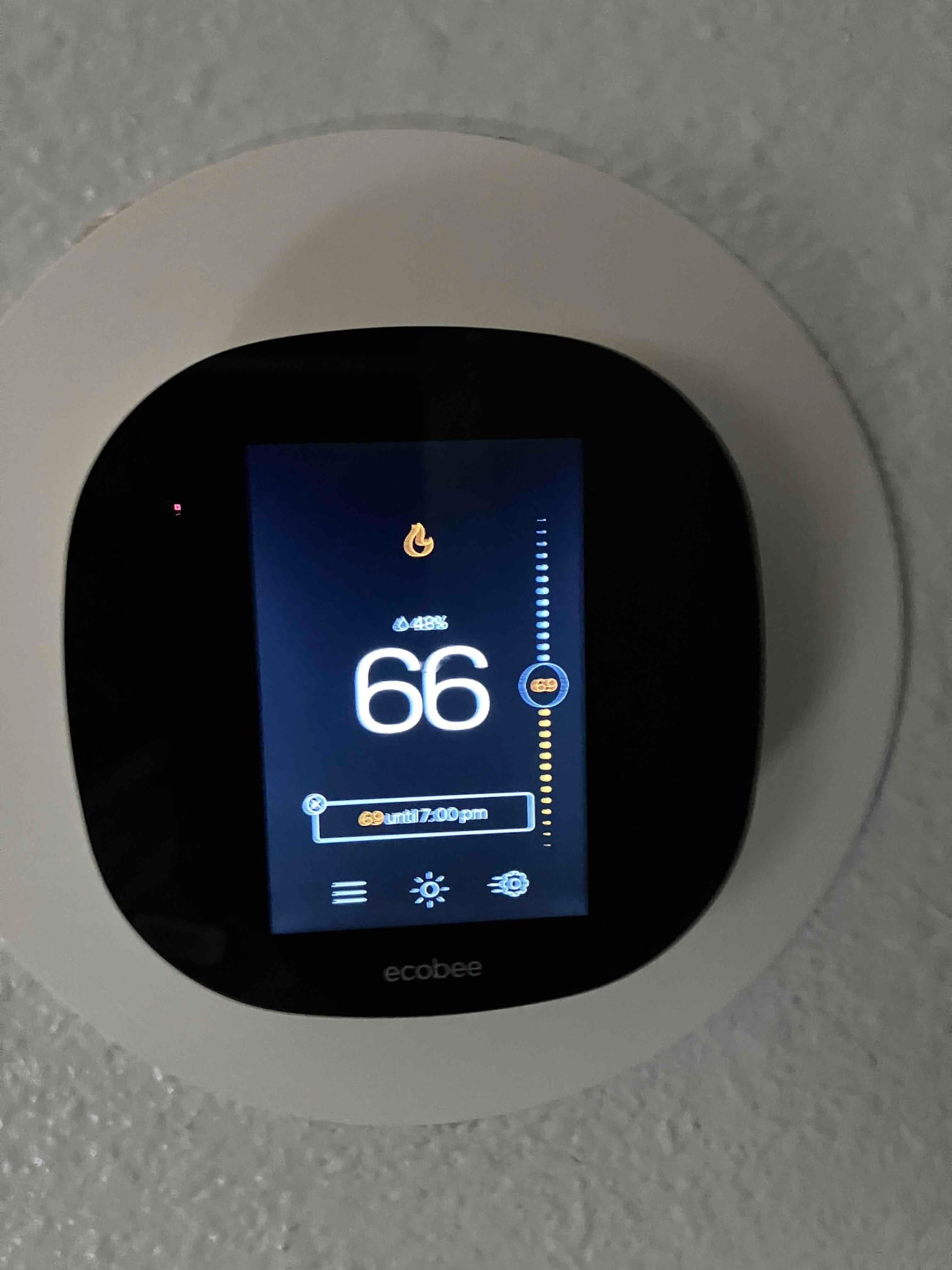 Wall-mounted smart thermostat displays a 66-degree setpoint with heating mode active, confirming new control installation and operation.