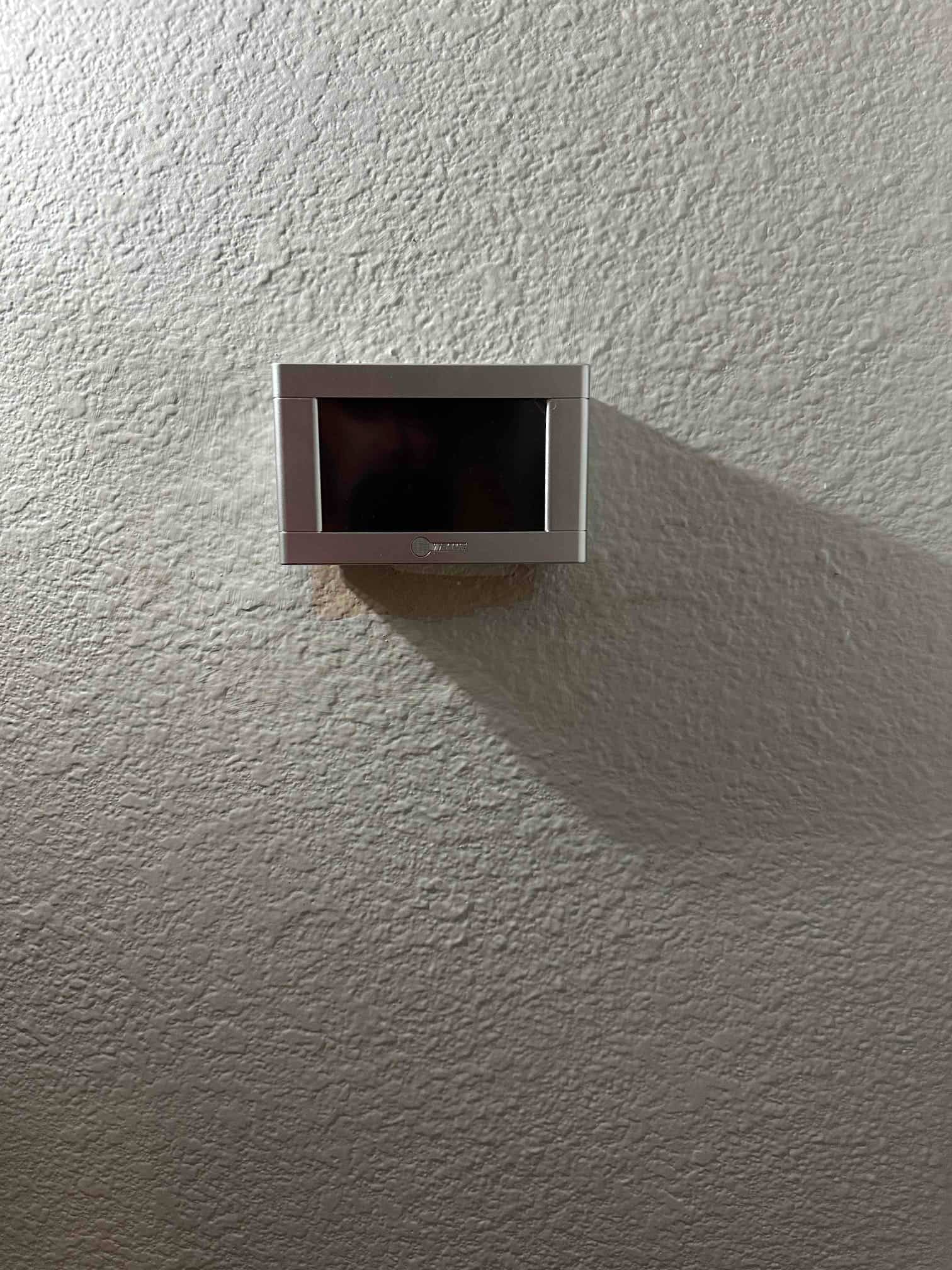 Wall-mounted thermostat installed with clean finish, centered on textured interior wall and ready for system commissioning.