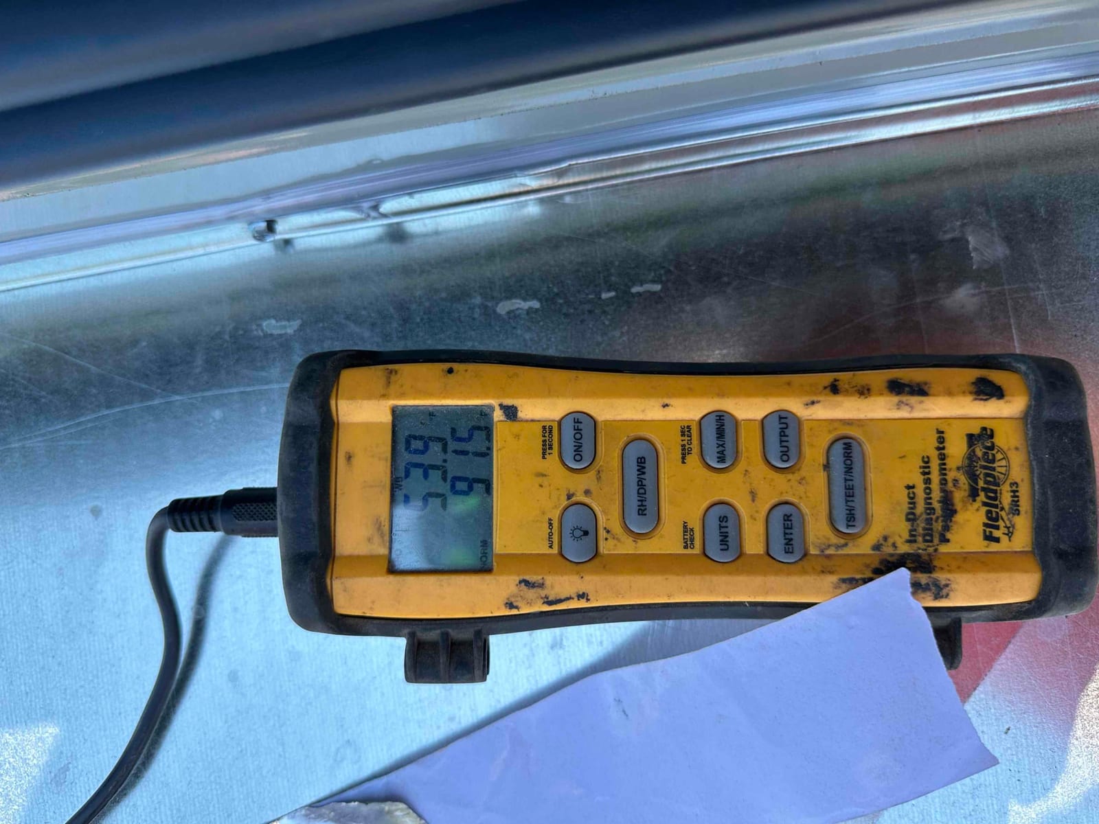 Digital duct thermometer displays 55.9 degrees Fahrenheit on the supply side during cooling performance verification.