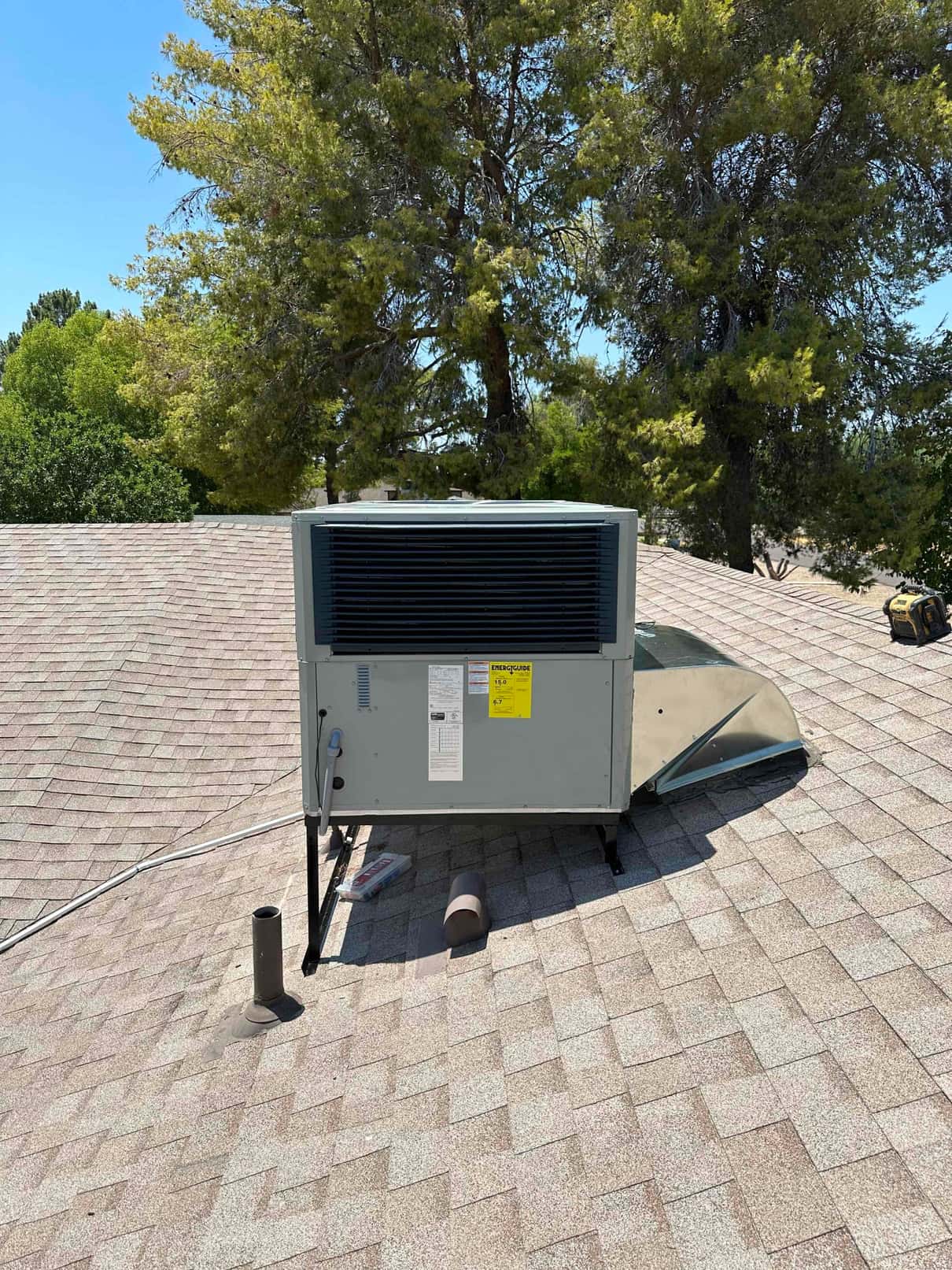 New rooftop package HVAC unit installed on standoffs with curb and sealed roof penetration visible on the shingle roof.
